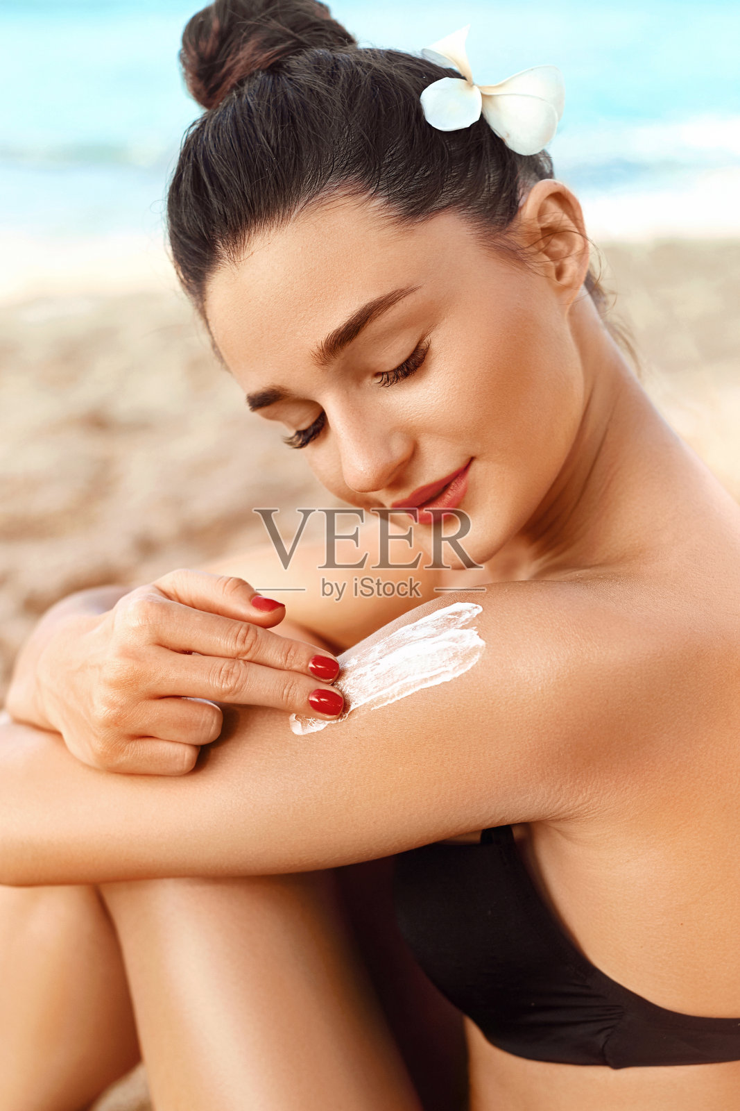 防晒霜。比基尼女子在晒黑的肩膀上涂防晒霜。防晒。皮肤和身体护理。女孩用防晒霜涂抹皮肤照片摄影图片