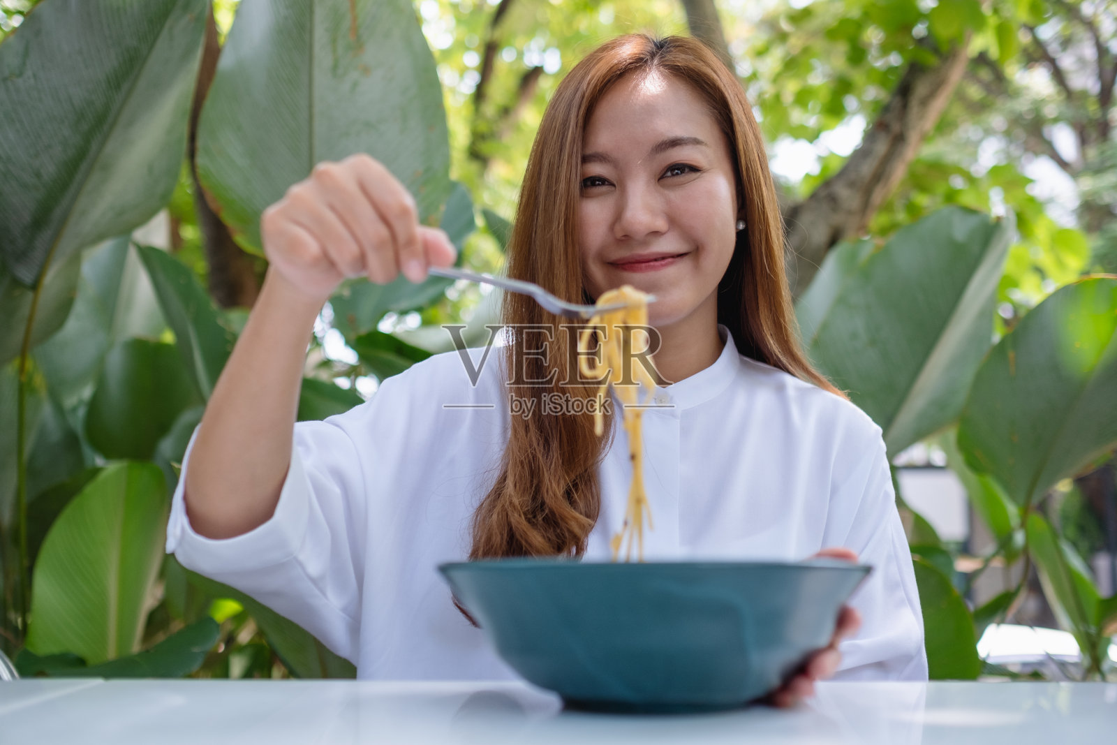 一个美丽的年轻女人在户外餐厅吃意大利面的肖像图像照片摄影图片