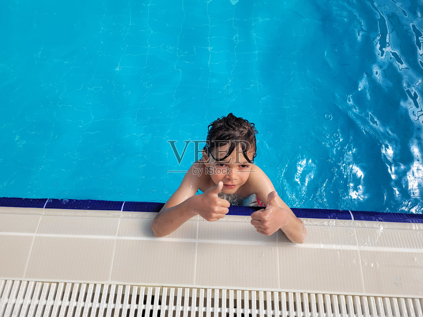 可爱的男孩刚在泳池里学游泳照片摄影图片