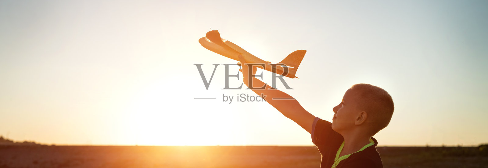 一个男孩在夕阳的天空中发射了飞机照片摄影图片