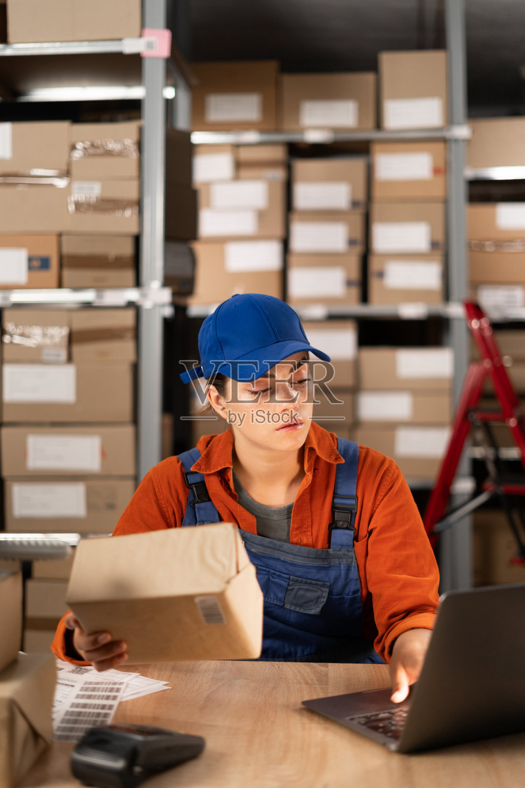 网上商店经理用笔记本电脑，准备包裹邮资。小企业主在仓库工作，为买家准备订单。照片摄影图片