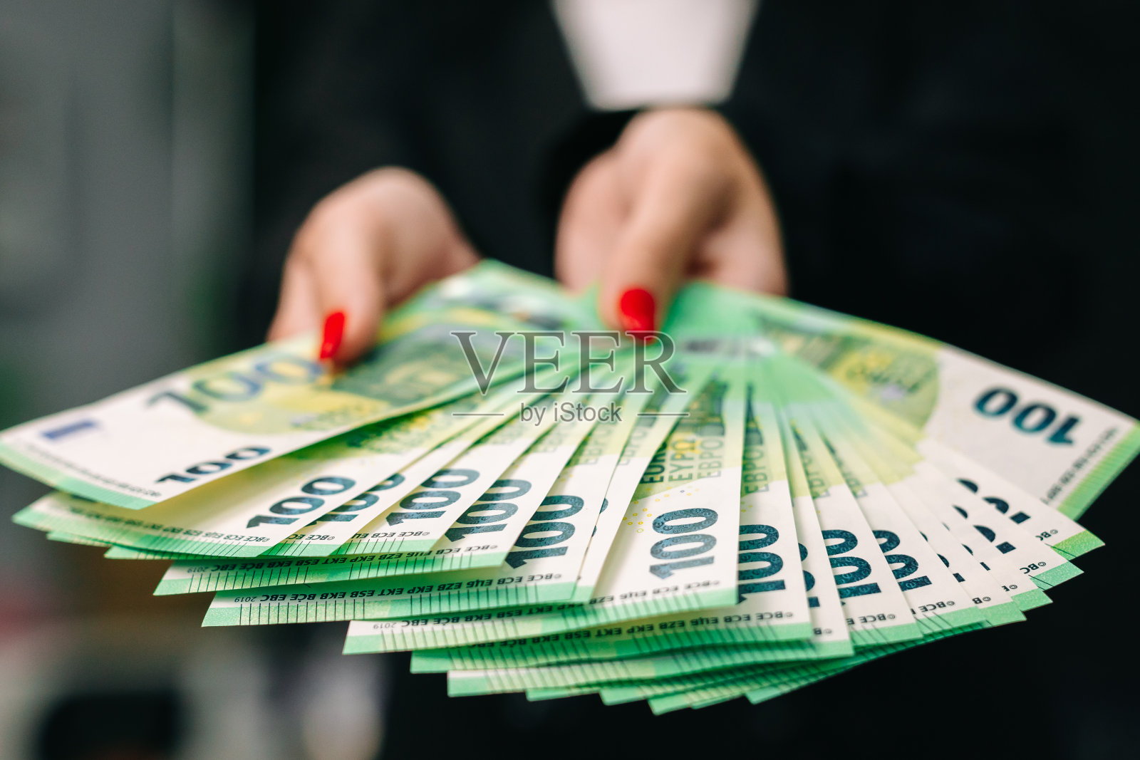 年轻女子商务女士，穿着别致的西装，穿着时尚，手里拿着一大笔欧元。业务和收入概念照片摄影图片