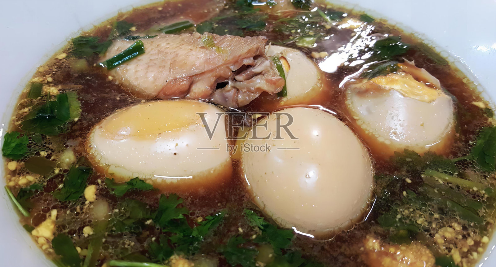 一碗有鸡蛋和肉的汤，一碗有三个鸡蛋和蔬菜的炖汤的照片。照片摄影图片