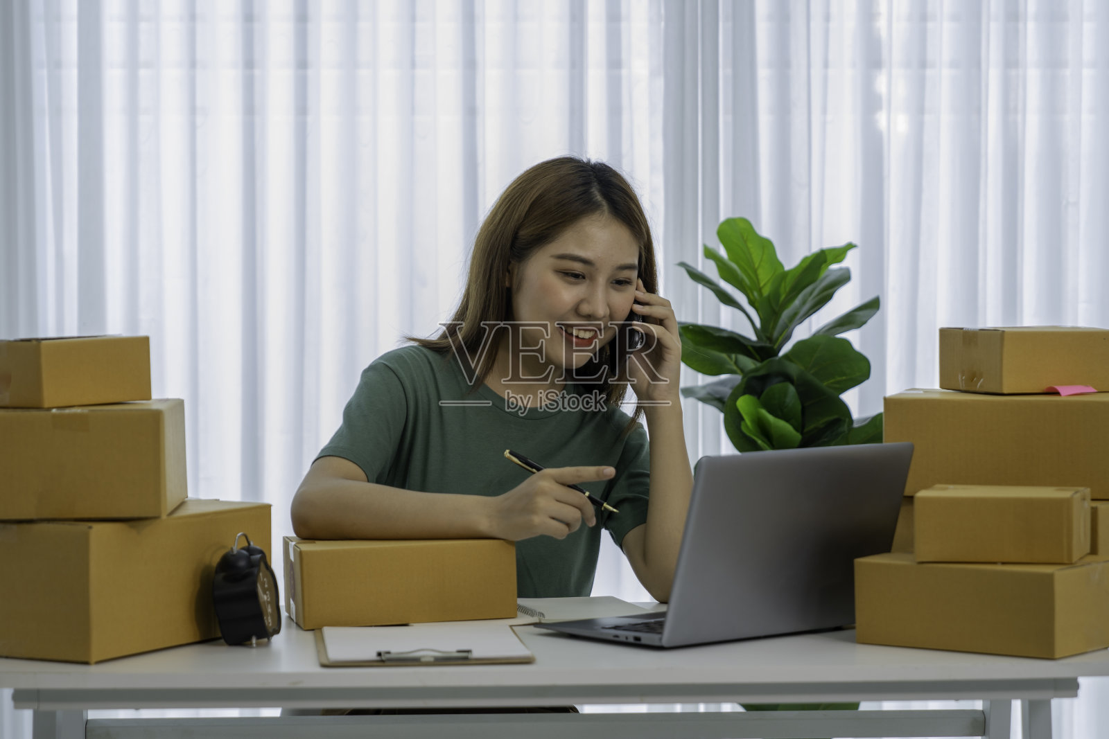 小企业主中小企业自由职业者妇女使用电话接收客户检查产品库存，在家办公，在线营销包装投递箱，中小企业电子商务的概念。照片摄影图片