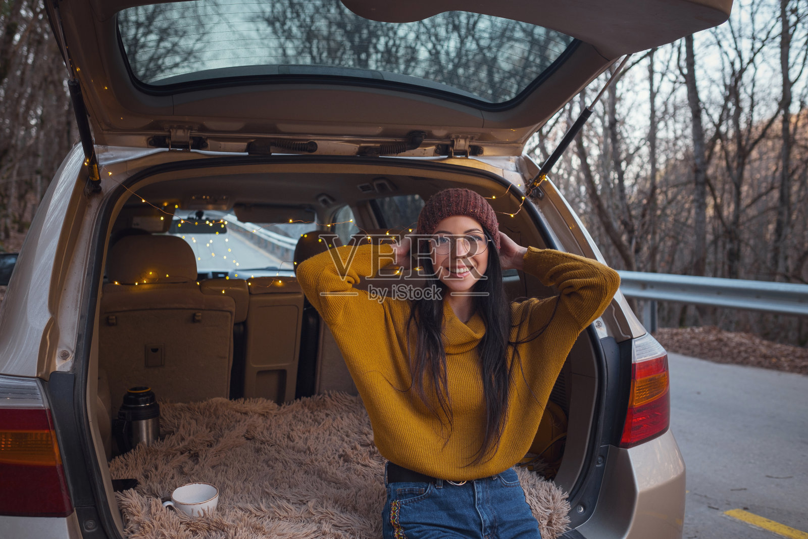 一个女人坐在汽车后备箱后面。准备出发了。照片摄影图片
