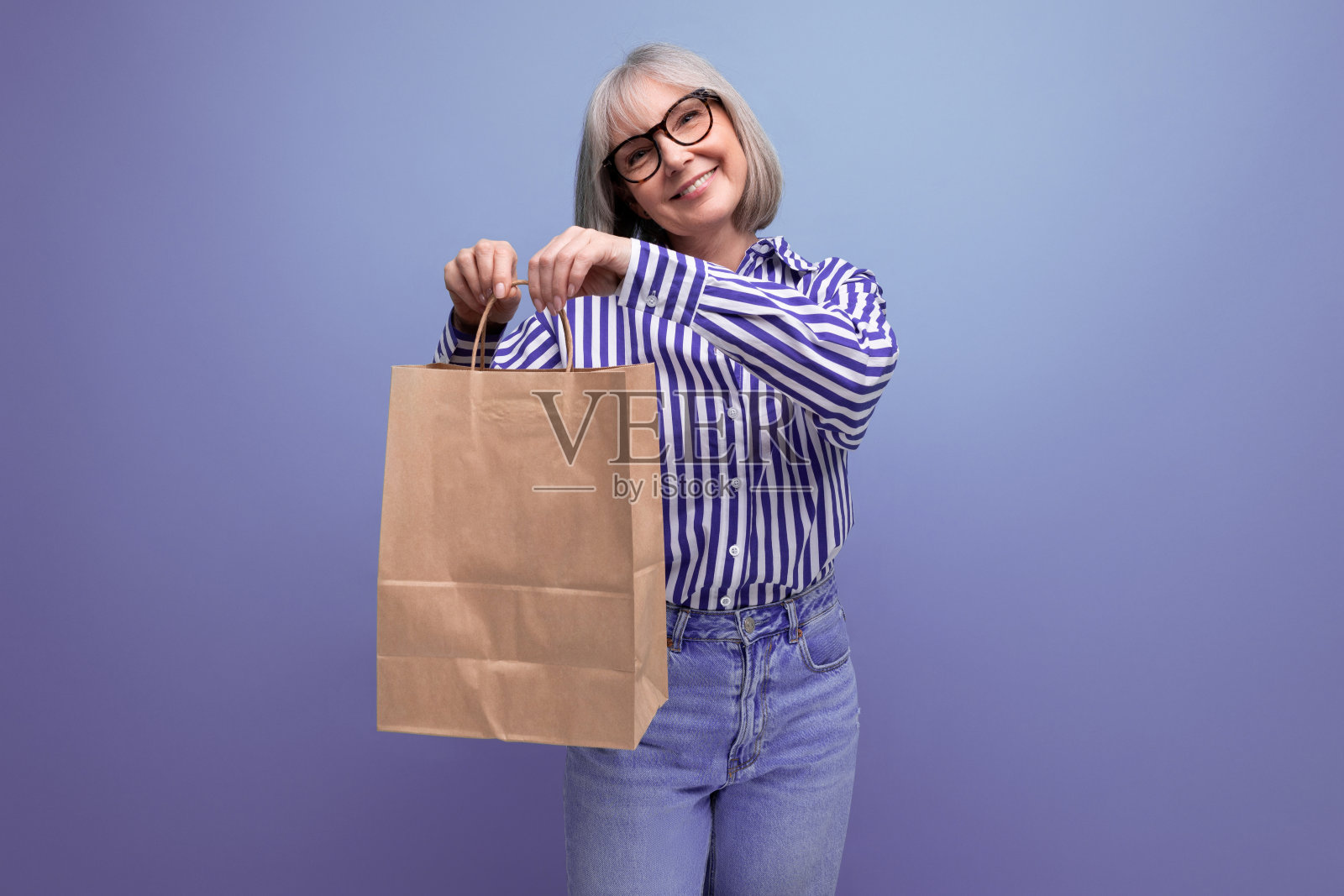 60多岁的退休妇女，头发花白，造型时髦，拿着一个手工包，上面有一个明亮的工作室背景，上面有复制空间照片摄影图片