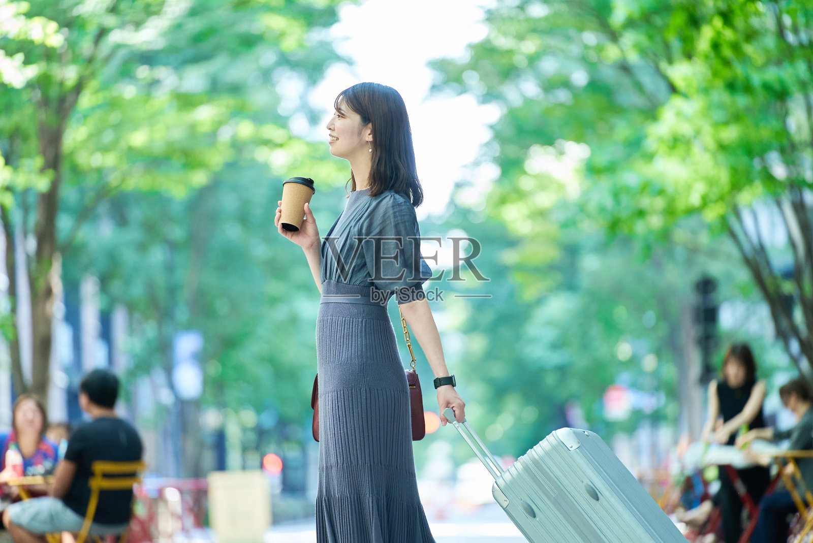 一个女人提着箱子走在城市里照片摄影图片