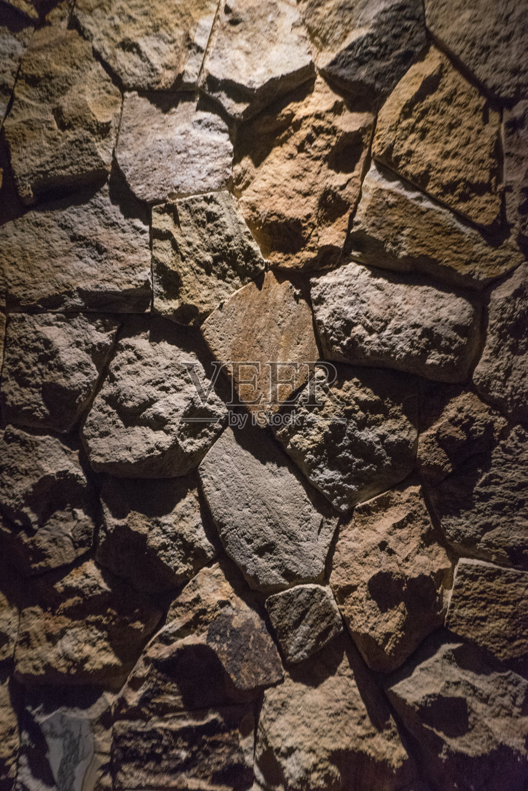 石头在墙上与聚光灯照明从顶部的一面照片摄影图片