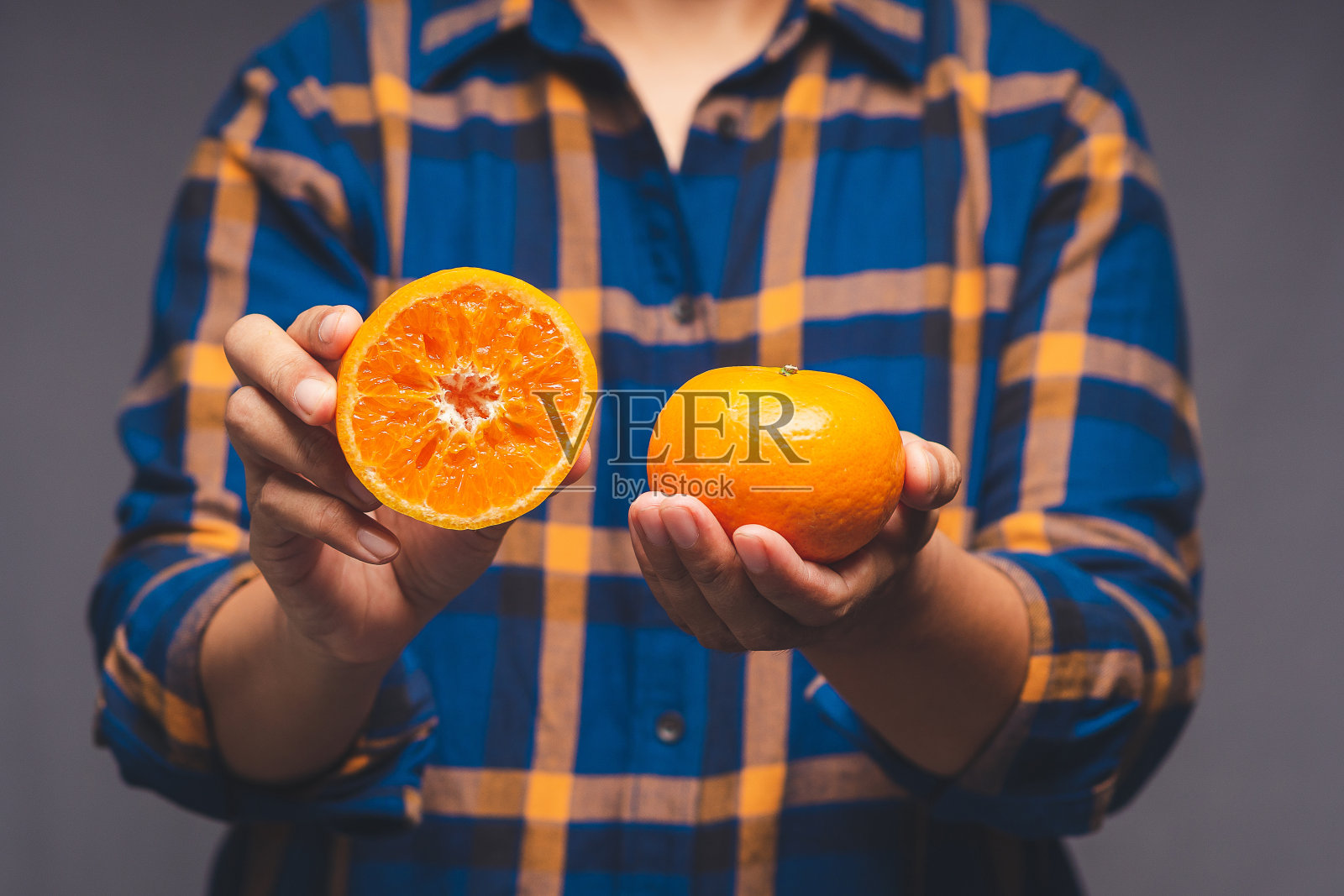 站在灰色背景上，手拿橘子的特写照片摄影图片