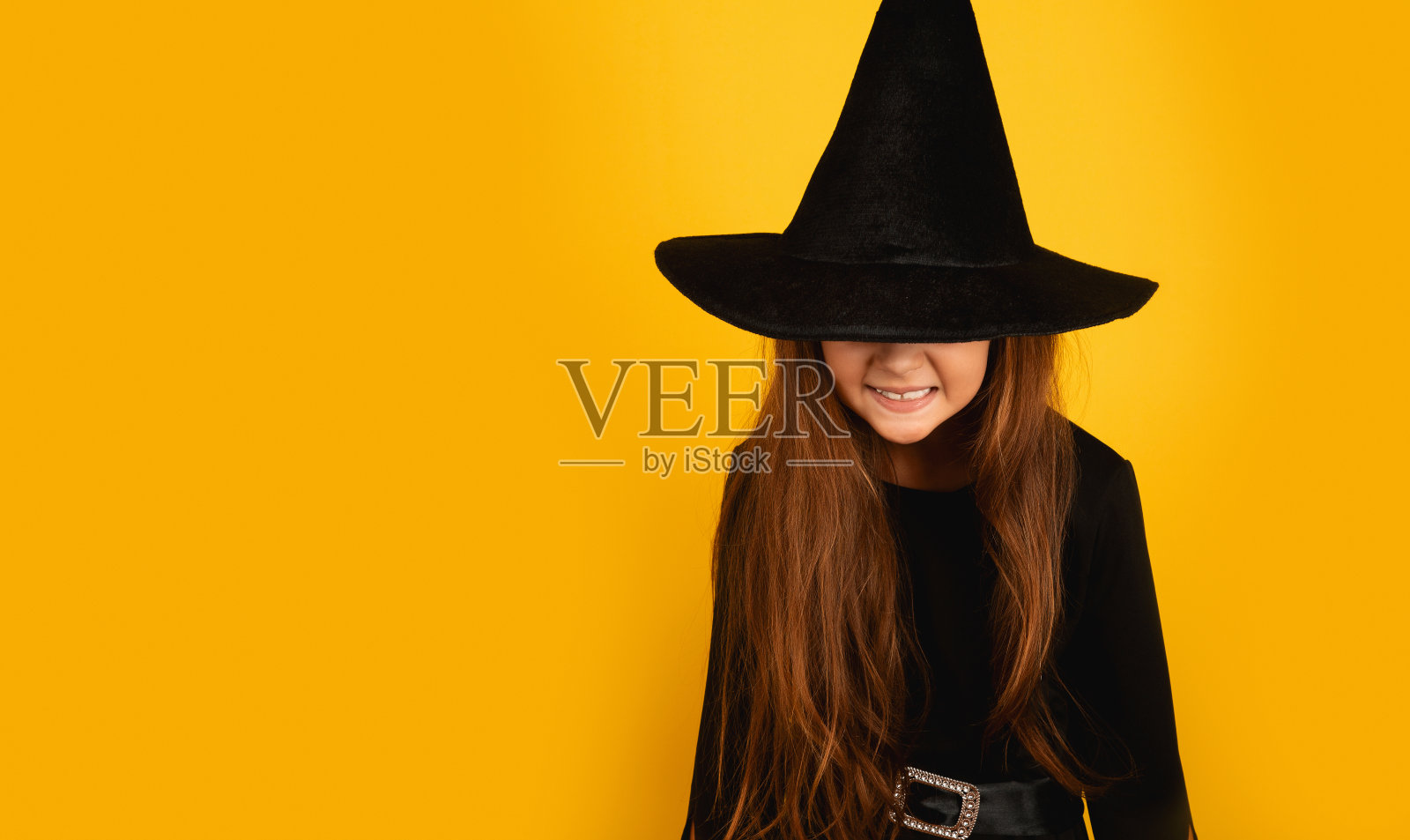 万圣节快乐!黄色背景上可爱的小女巫。本空间照片摄影图片