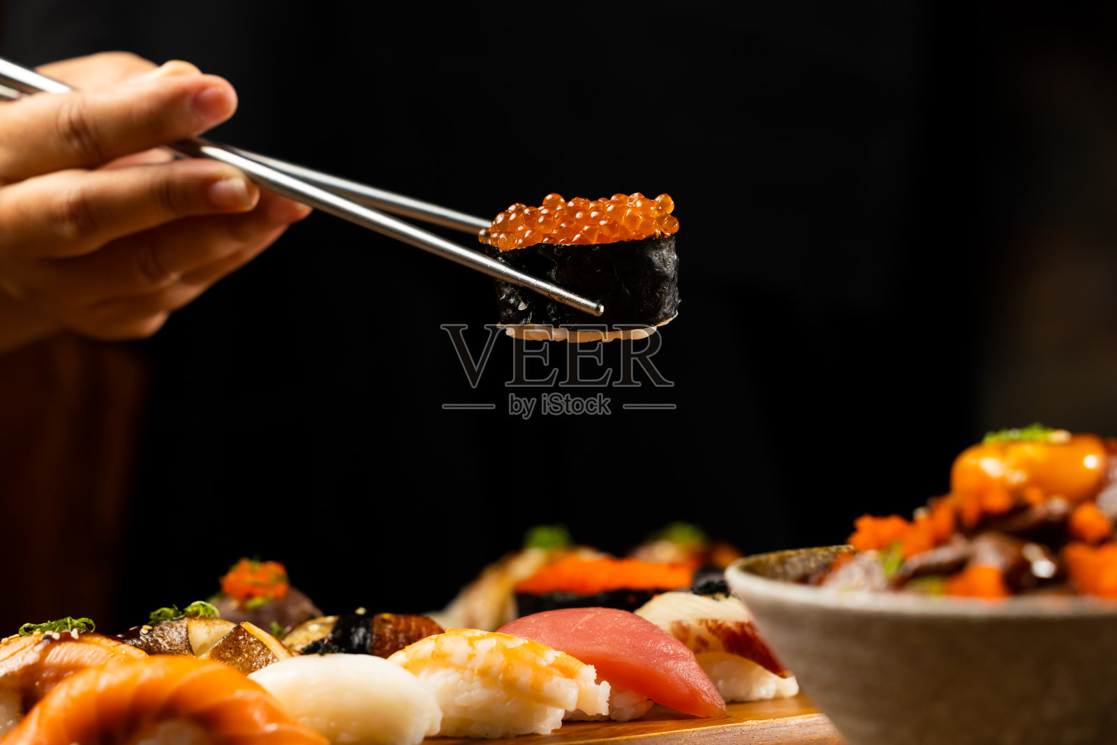 近距离用筷子吃寿司。什锦日本寿司。寿司配金枪鱼、螃蟹、鲑鱼、鳗鱼和面包卷。日本食物被隔离在白色背景上照片摄影图片