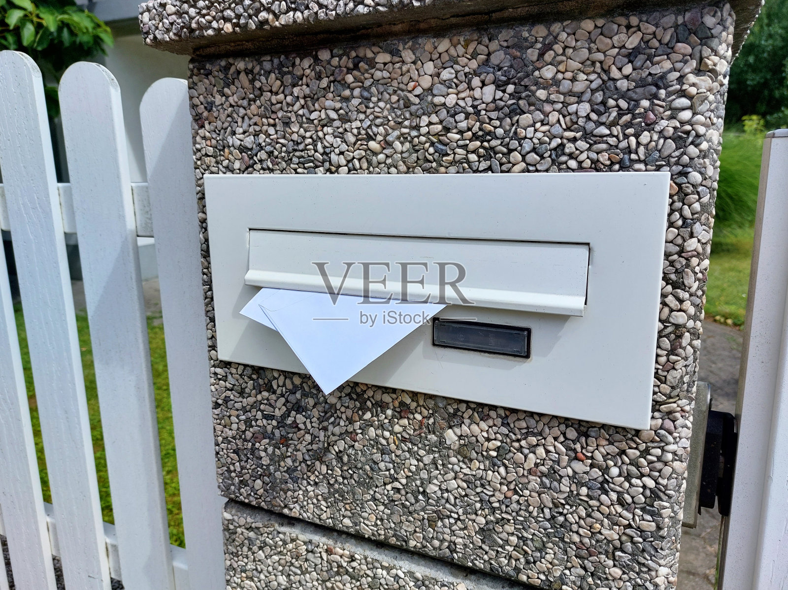 白色栅栏上的邮筒——信箱里的信照片摄影图片