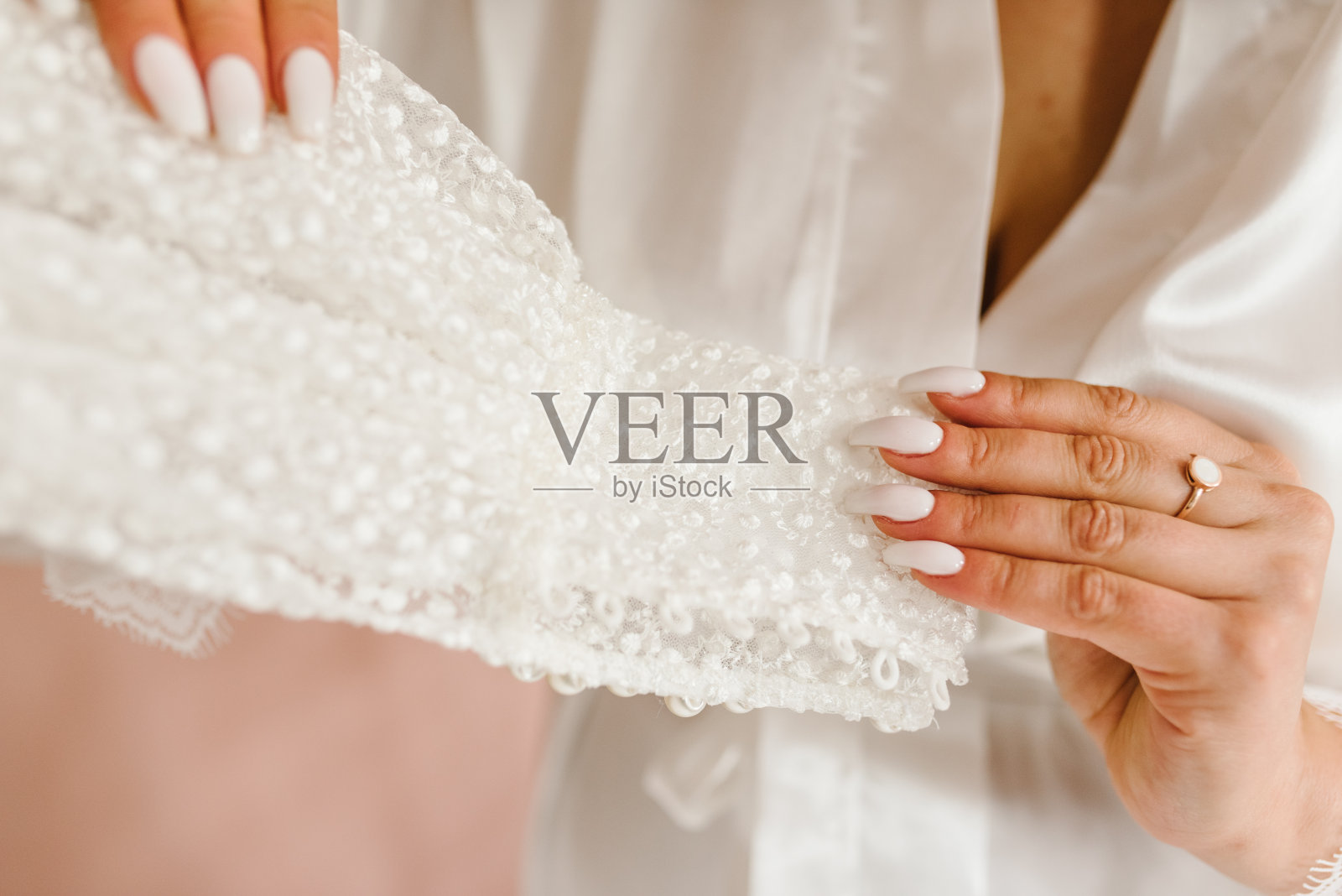 新娘在房间里拿着婚纱，女孩在家里穿着睡衣。准备早上的婚礼。关闭了。照片摄影图片