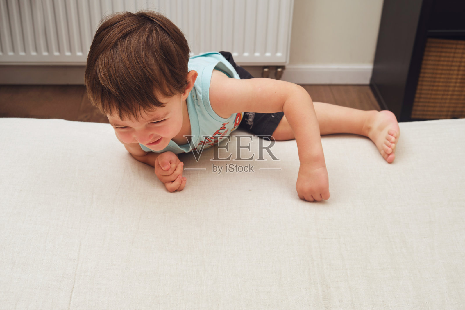 婴儿在床沿上爬，有发生室内事故的危险。两岁儿童(两岁男童)照片摄影图片