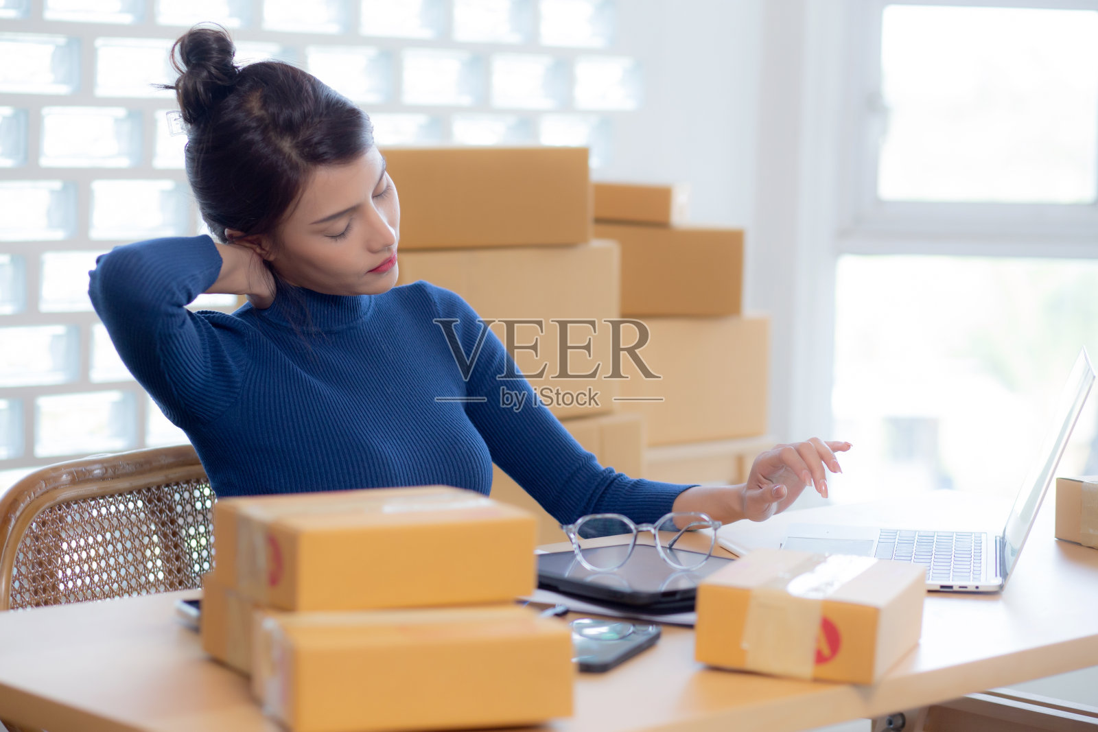 年轻的亚洲女性在网上销售送货服务，而女性办公室综合症颈部疼痛，因为在家里工作过度，网上航运，自由职业者做小企业或中小企业和零售。照片摄影图片
