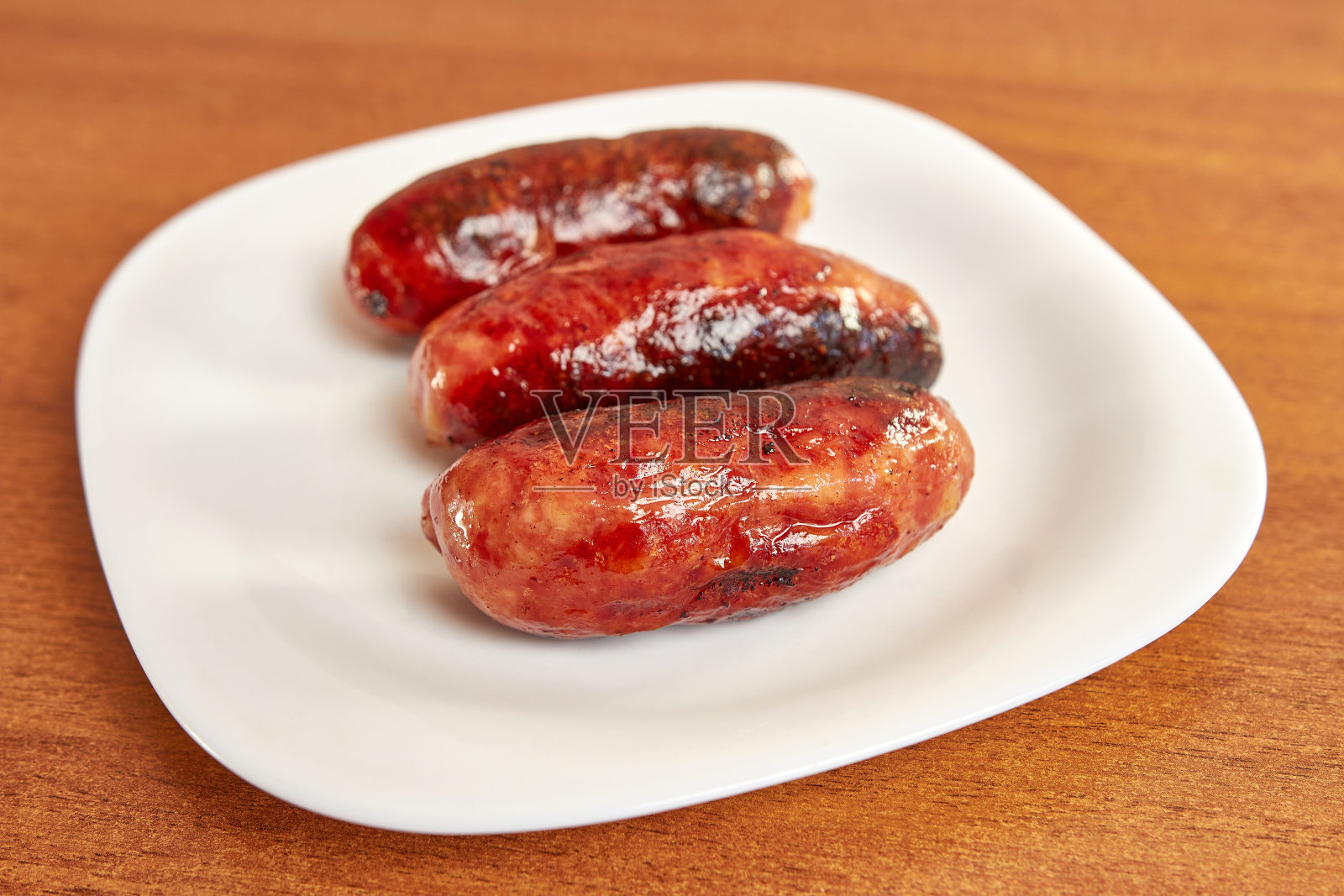 白色盘子里的煎香肠。照片摄影图片