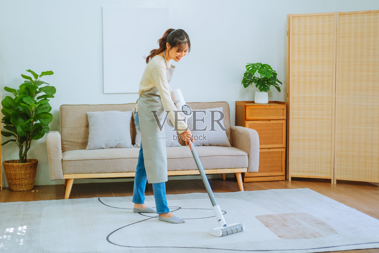 亚洲妇女使用真空吸尘器清洁地板。管理的概念照片摄影图片