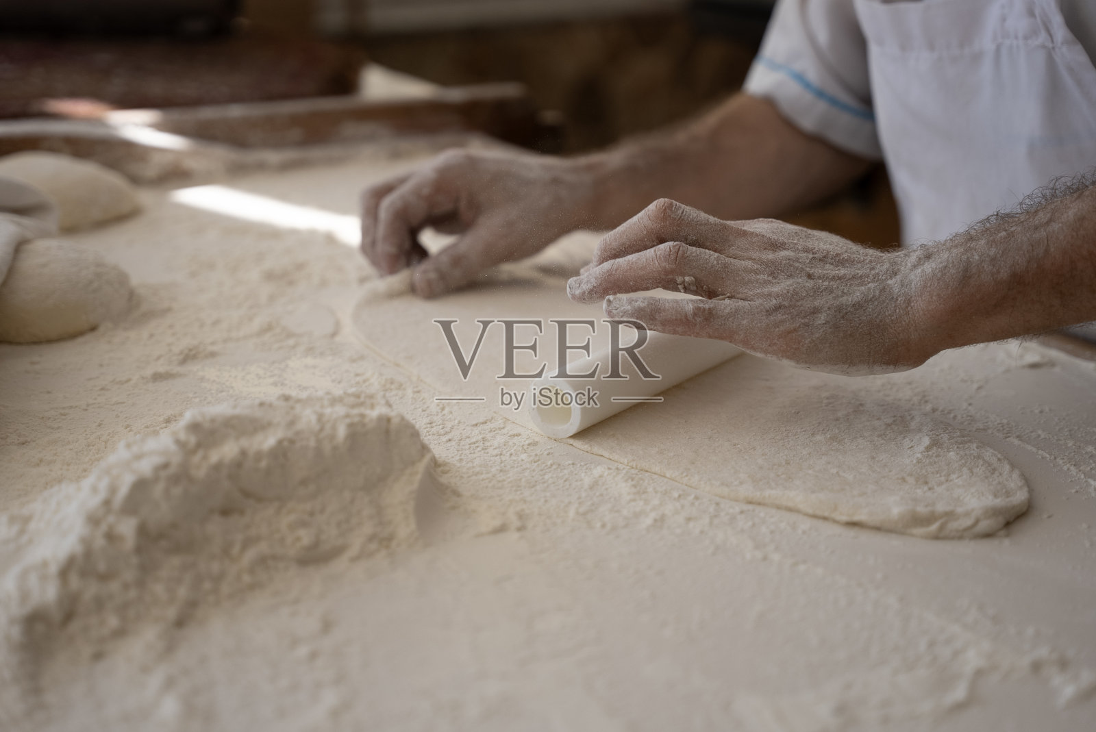 一个老人在面包店做面包，把面团铺好照片摄影图片