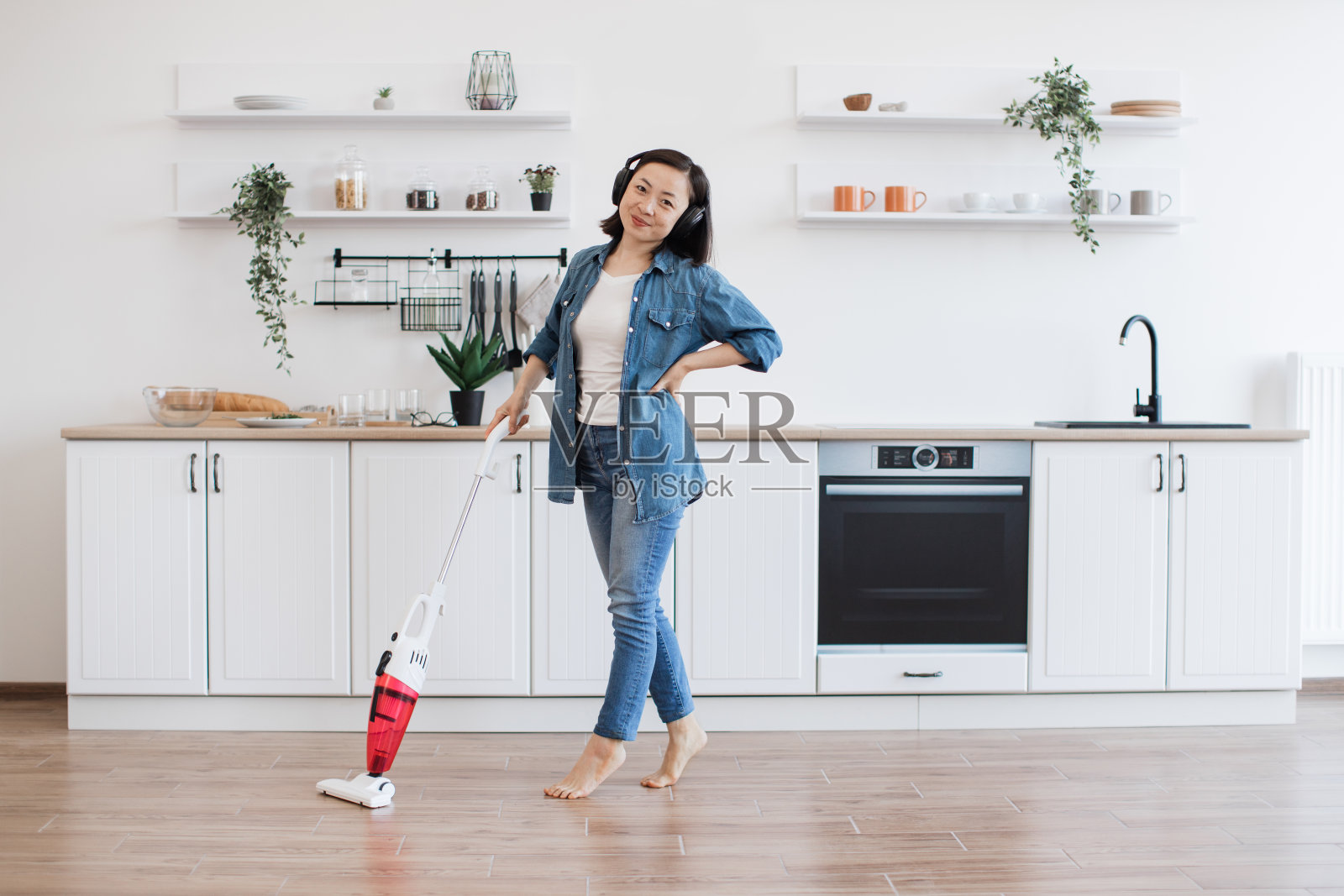 女士一边用吸尘器一边听厨房里的音乐照片摄影图片