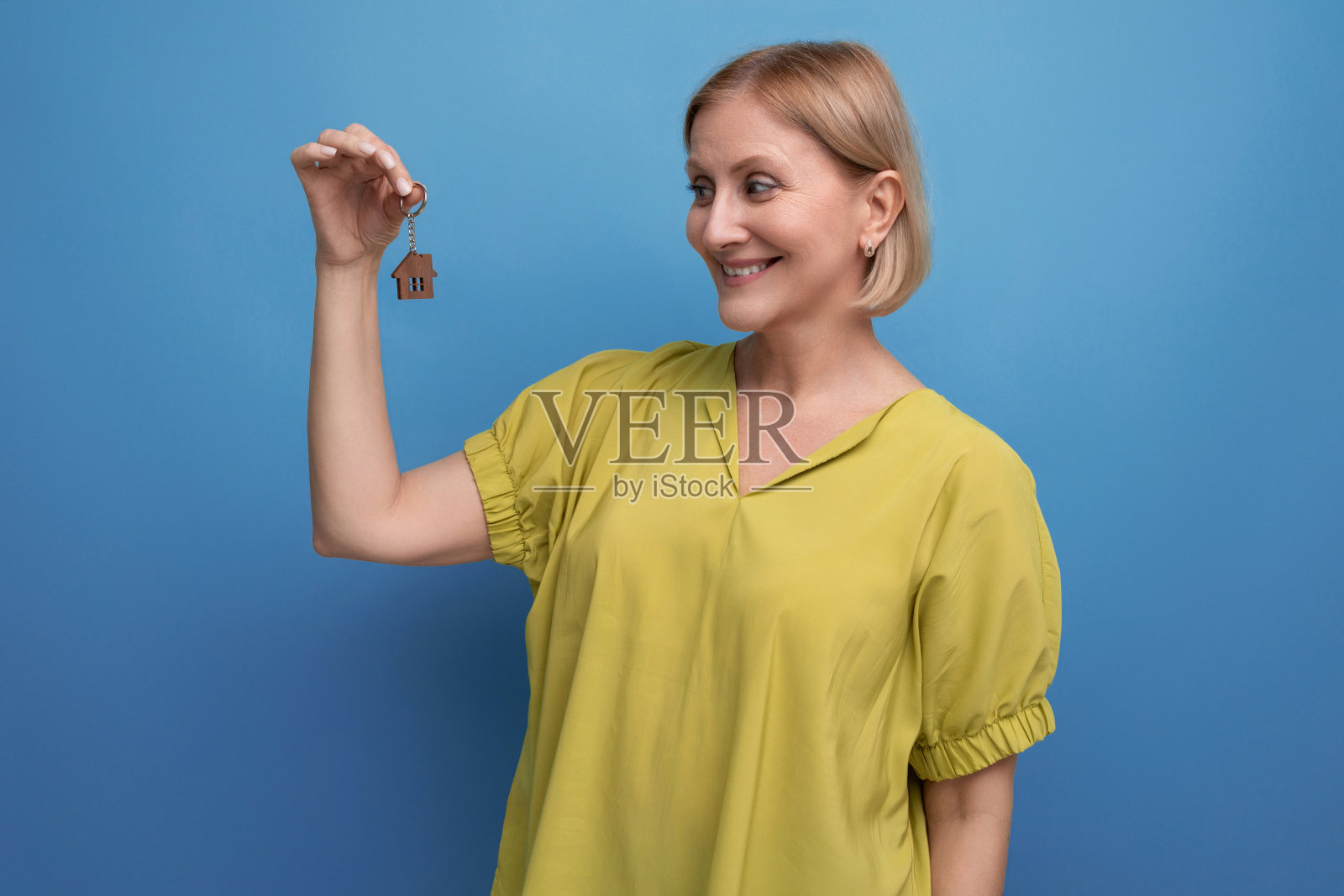 幸福的金发中年女人的肖像，拿着新房子的钥匙照片摄影图片