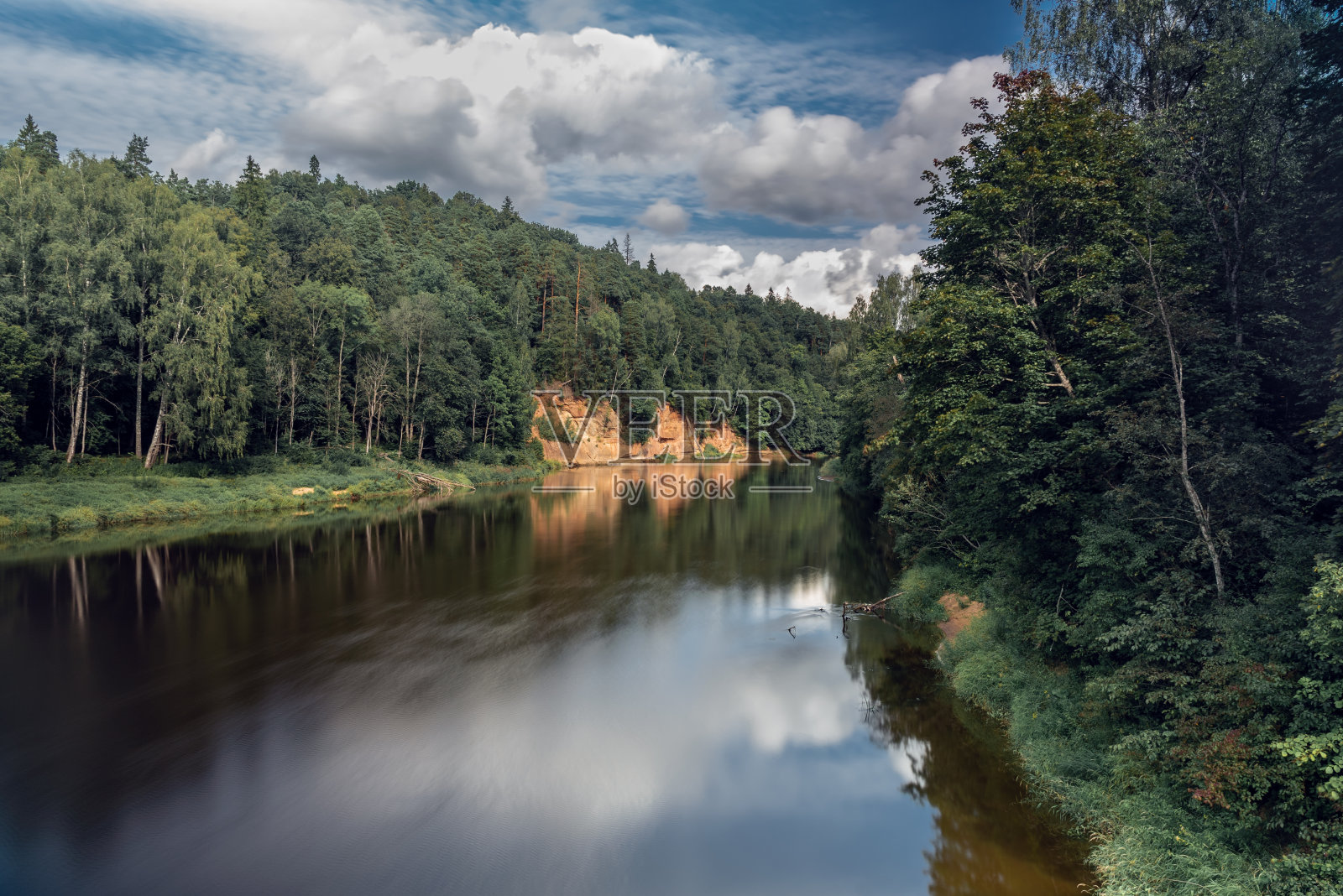 红色砂岩魔鬼洞穴悬崖(拉脱维亚语:Velnalas klintis)的景观视图，在西古尔达的高加河，拉脱维亚八月多云的一天照片摄影图片