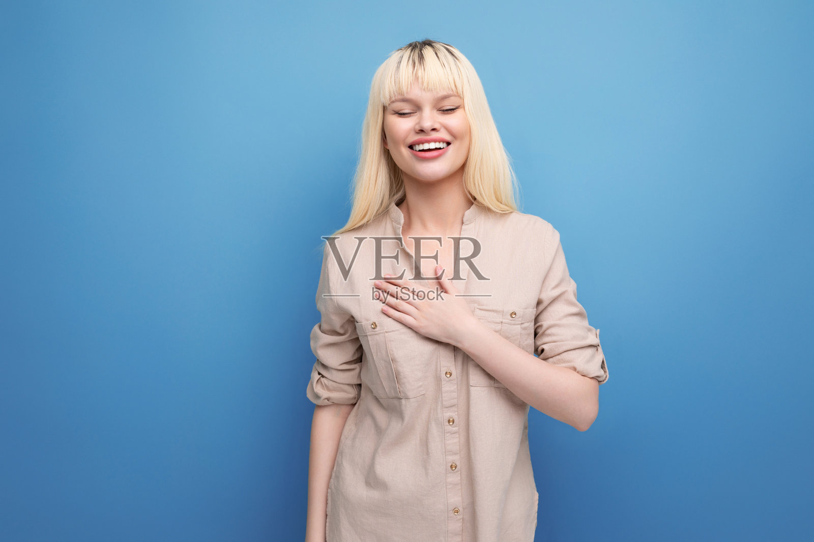 一个迷人的金发女郎的肖像在一个蓝色的背景上的衬衫与复制空间照片摄影图片