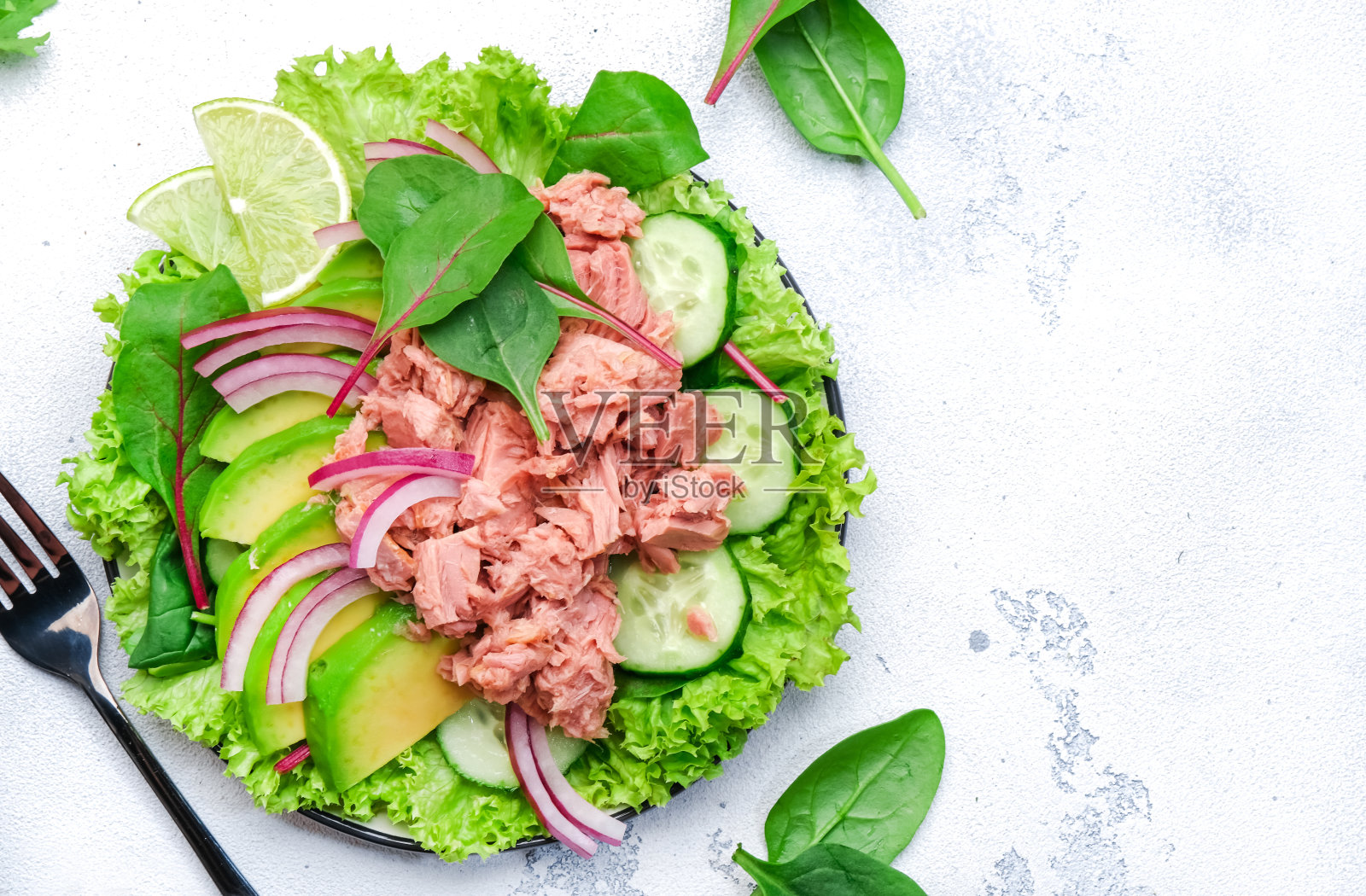 金枪鱼沙拉罐头配牛油果、黄瓜、洋葱、菠菜、生菜和酸橙。白色桌面背景，俯视图照片摄影图片