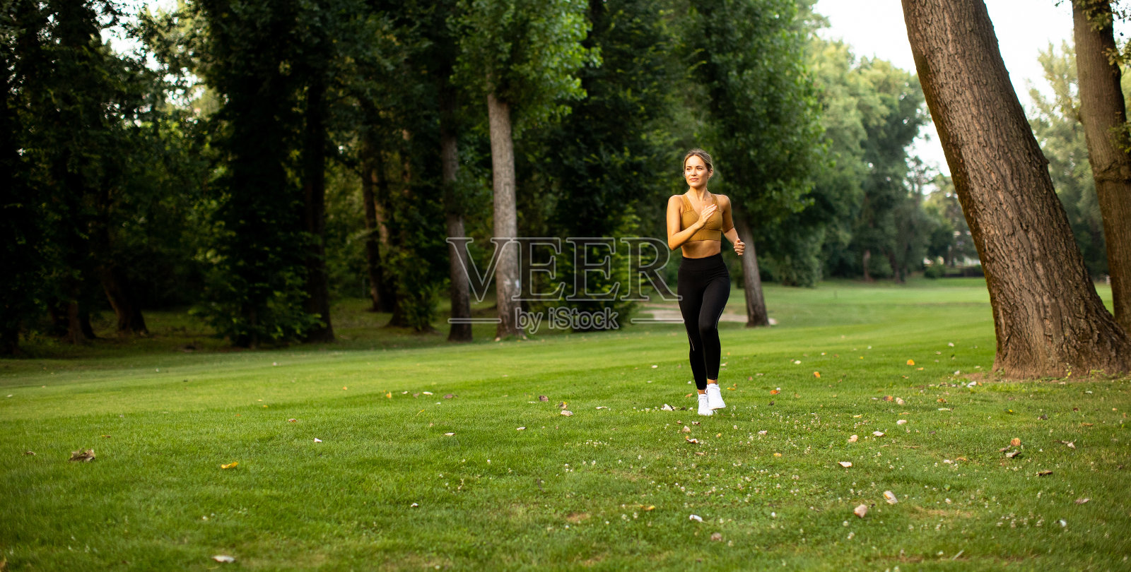 漂亮的年轻女子在公园里跑步照片摄影图片