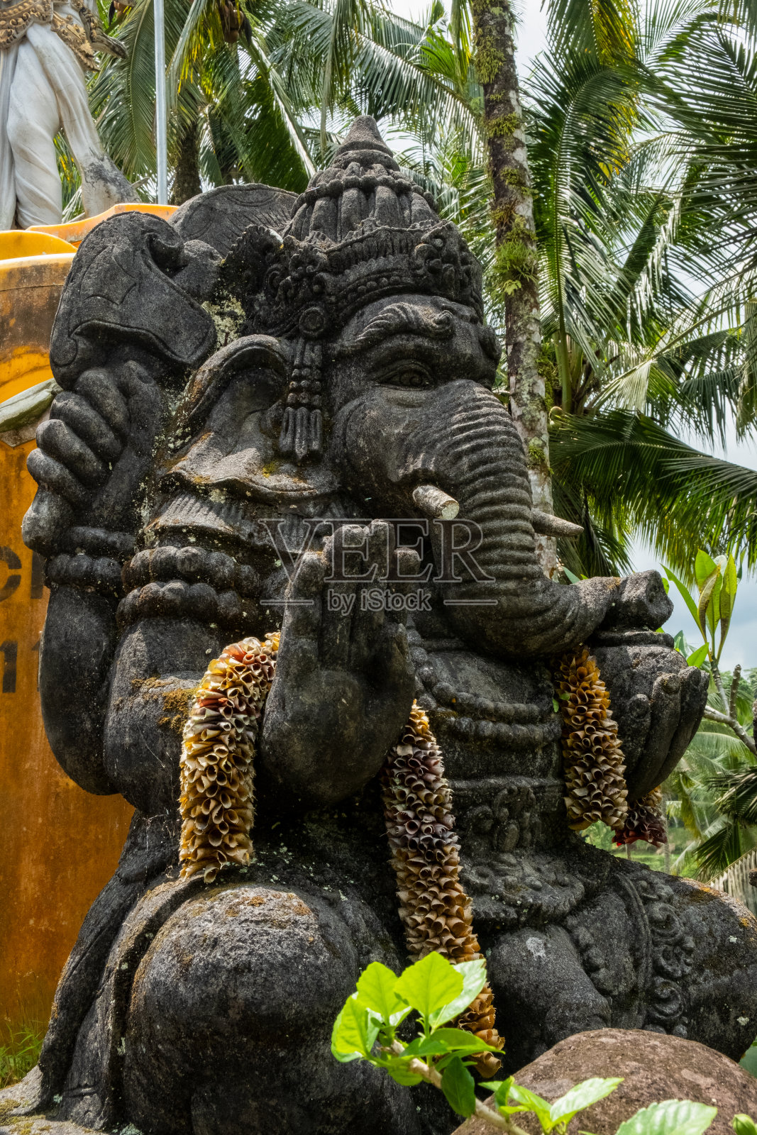在雨林中，传统的石雕神话中的大象和牛的形象被一个鸟粪弄脏了，背景是树枝和高大的树木。猴林，乌布，巴厘岛，印度尼西亚。照片摄影图片