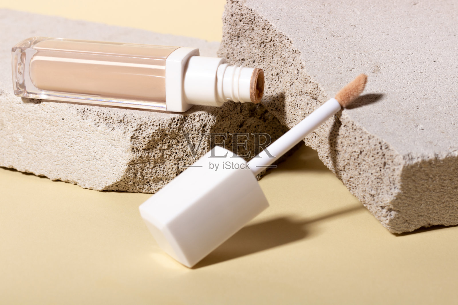 粉底、遮瑕在背景石上形成几何形状。带有复制空间的米色背景上的面校正器。包装模型与拷贝空间照片摄影图片