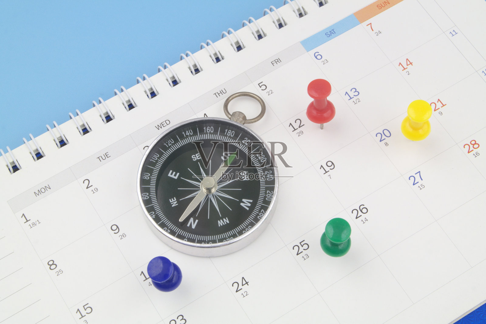 日历页上带有图钉的指南针。照片摄影图片
