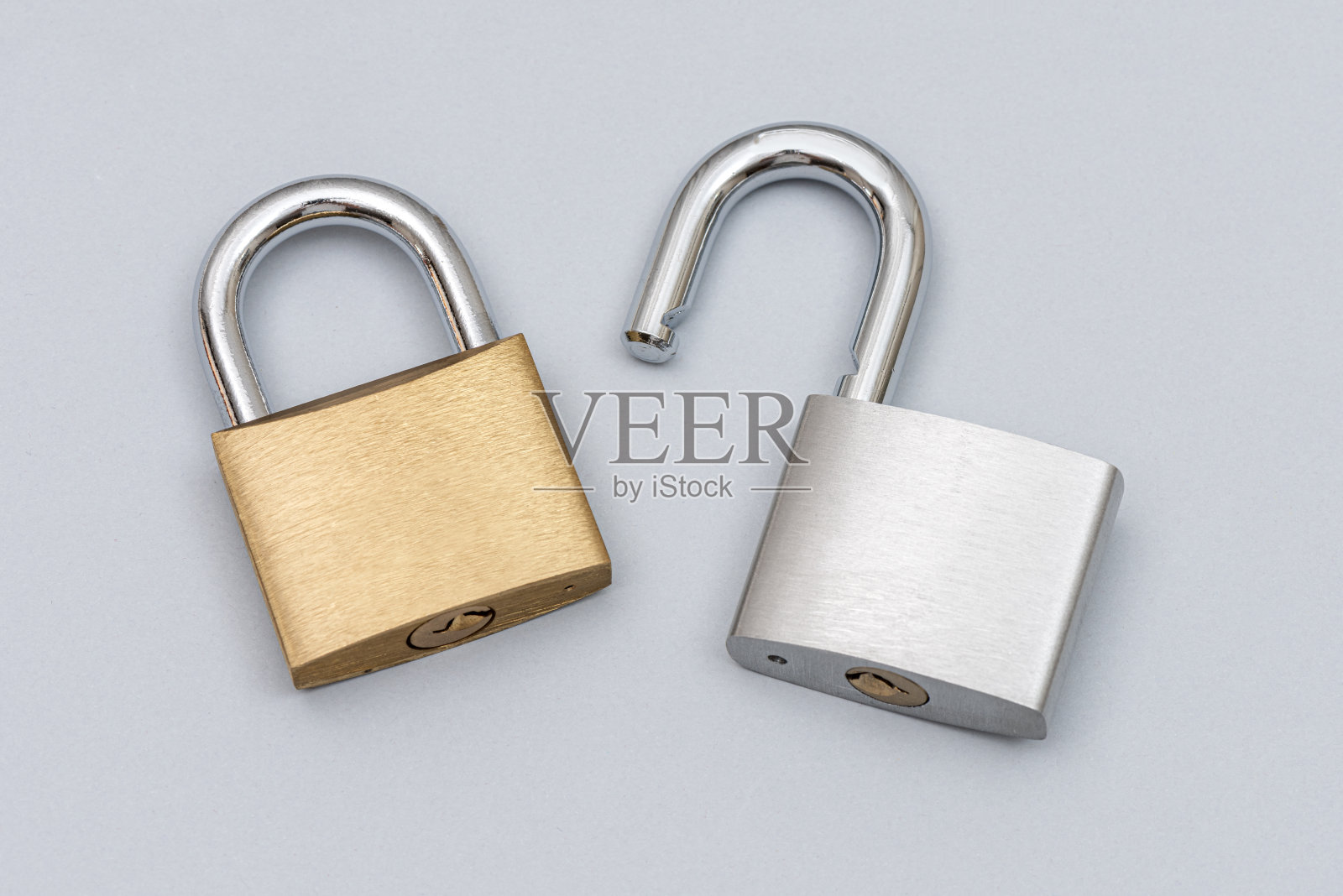 锁定金色解锁银色挂锁在灰色背景上。照片摄影图片