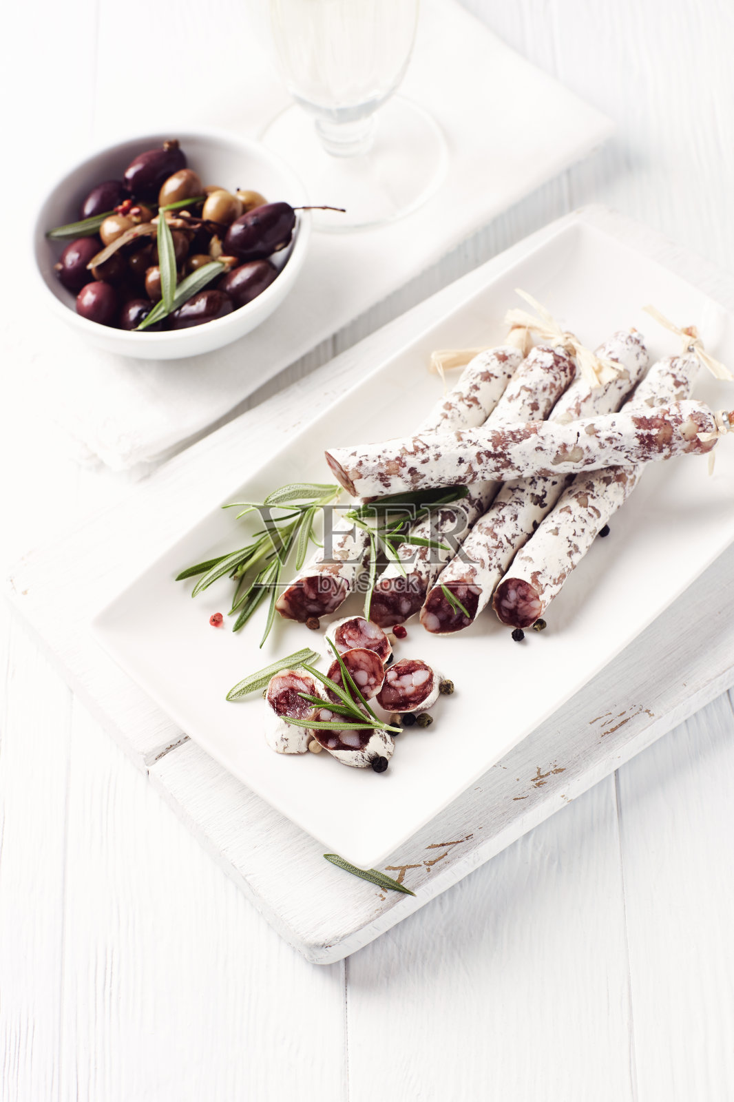 切片的法国腊肠配上新鲜的迷迭香和橄榄，白色背景照片摄影图片