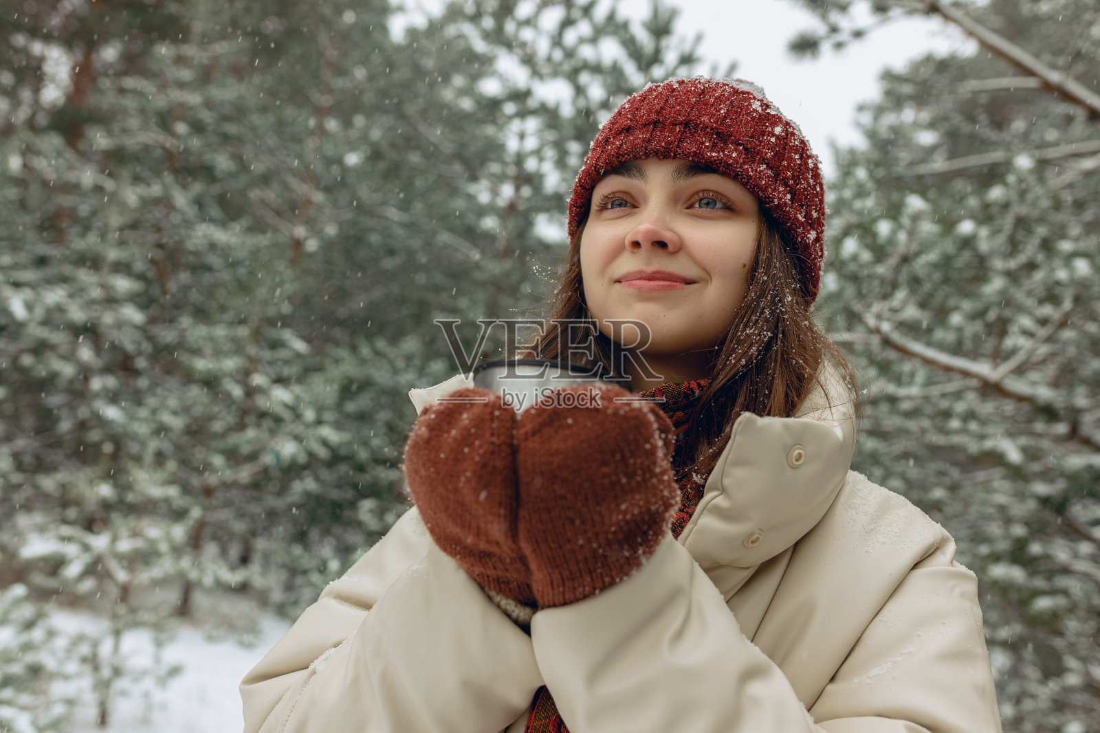 冬天的森林里，女人拿着一大杯热茶照片摄影图片