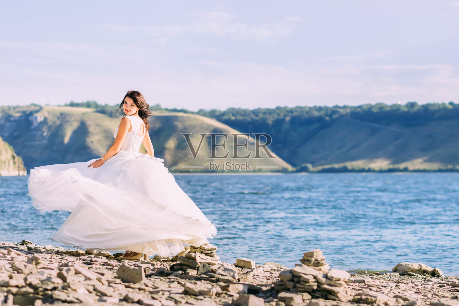 美丽的新娘穿着奢华的白色礼服在湖边旋转照片摄影图片