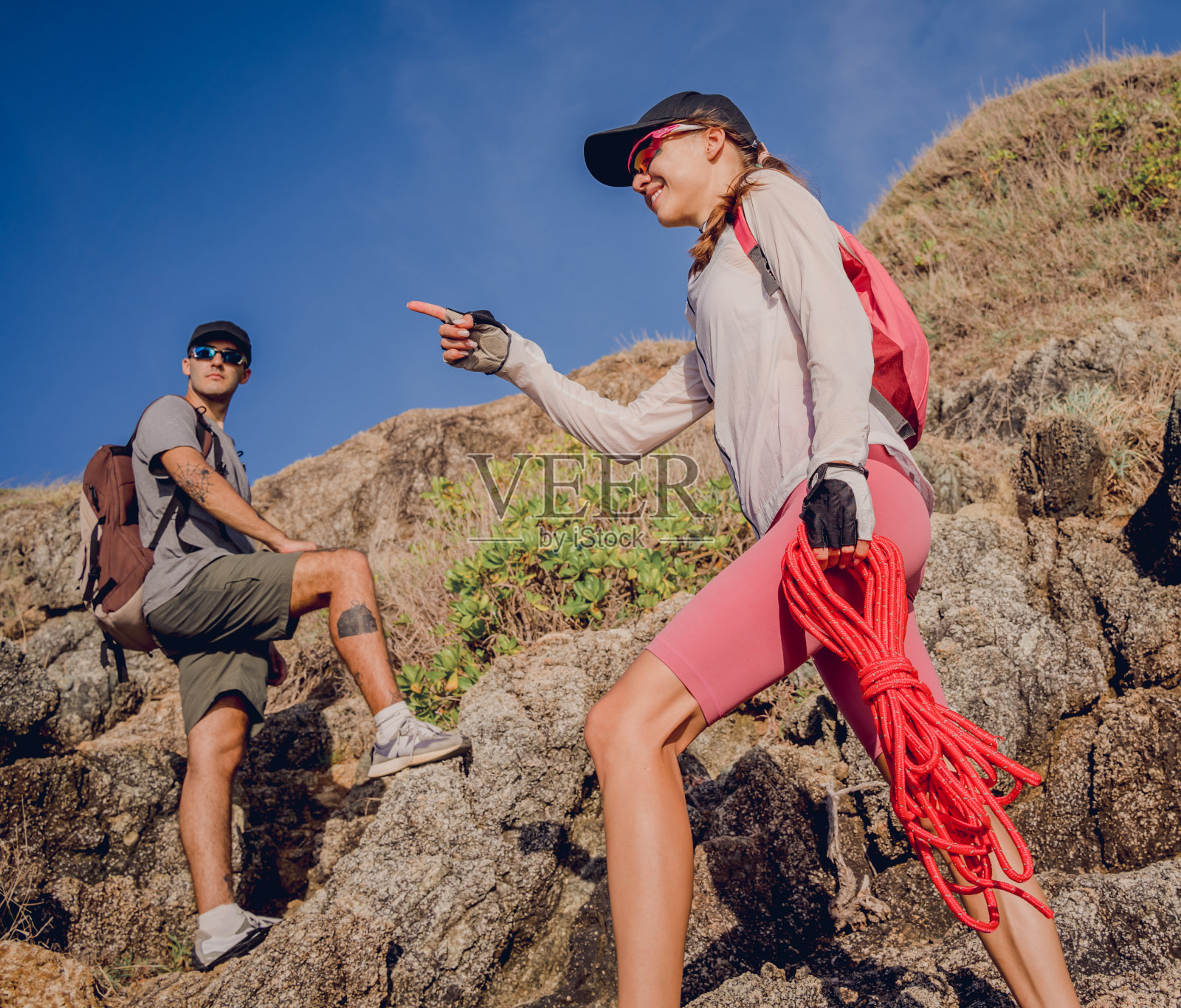 一对年轻夫妇用绳子爬到海边的山顶照片摄影图片