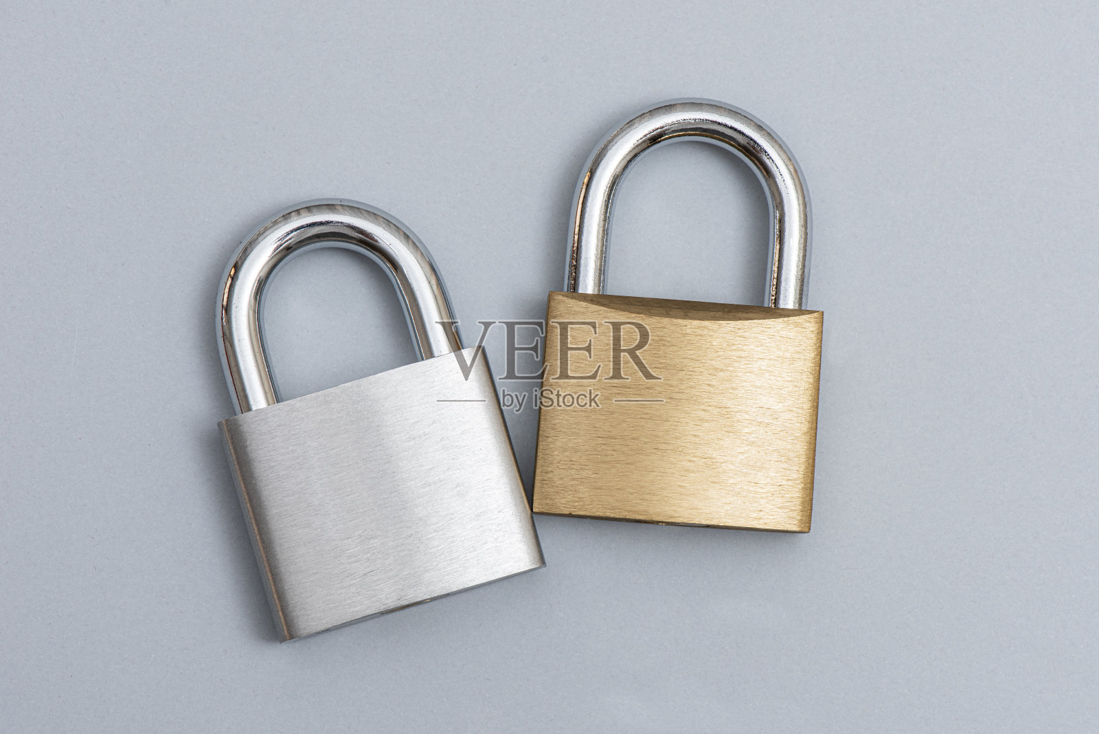 银色和金色的锁锁在灰色的背景上。照片摄影图片