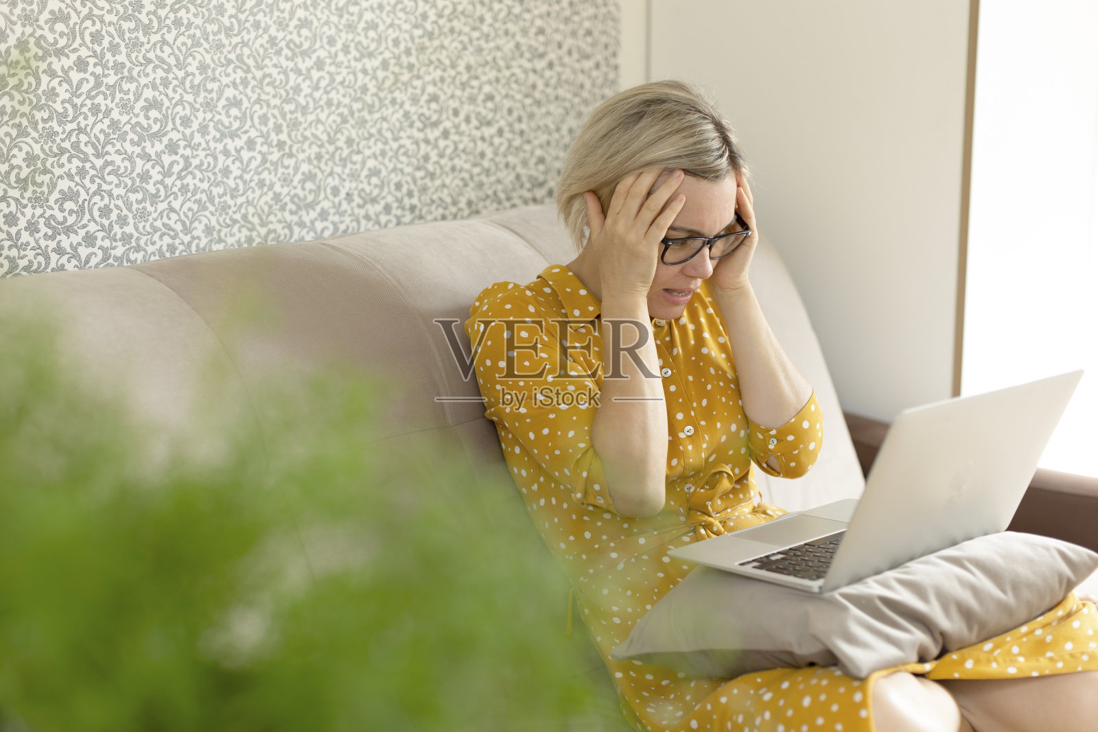 这个女人很焦虑，抓着她的头看着她的笔记本电脑。照片摄影图片