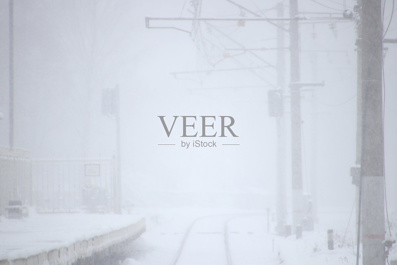 白雪覆盖的铁轨，远处有一个火车站。冬天的背景。照片摄影图片