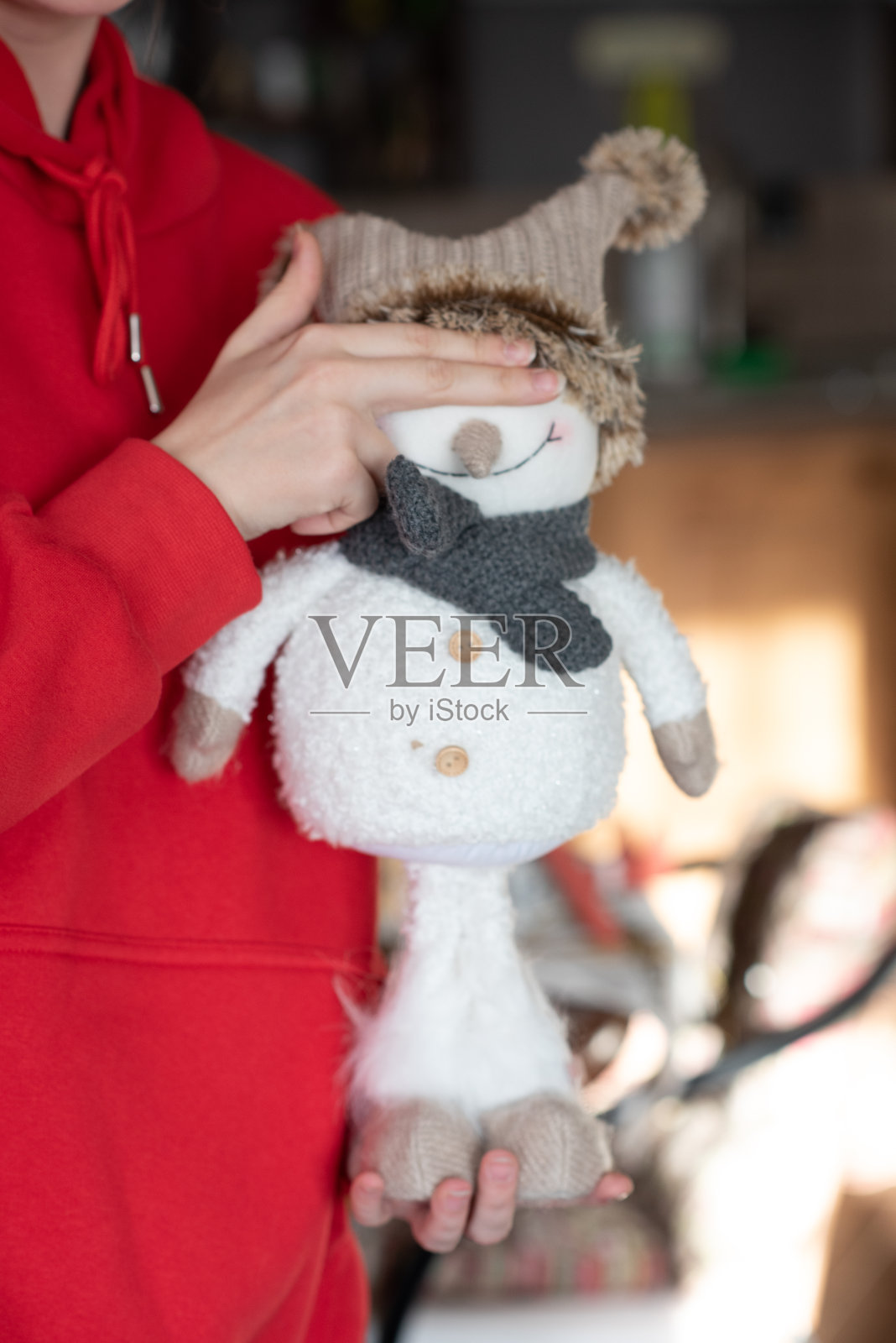 一个女孩和一个雪人。一个穿红色连帽衫的女人。照片摄影图片