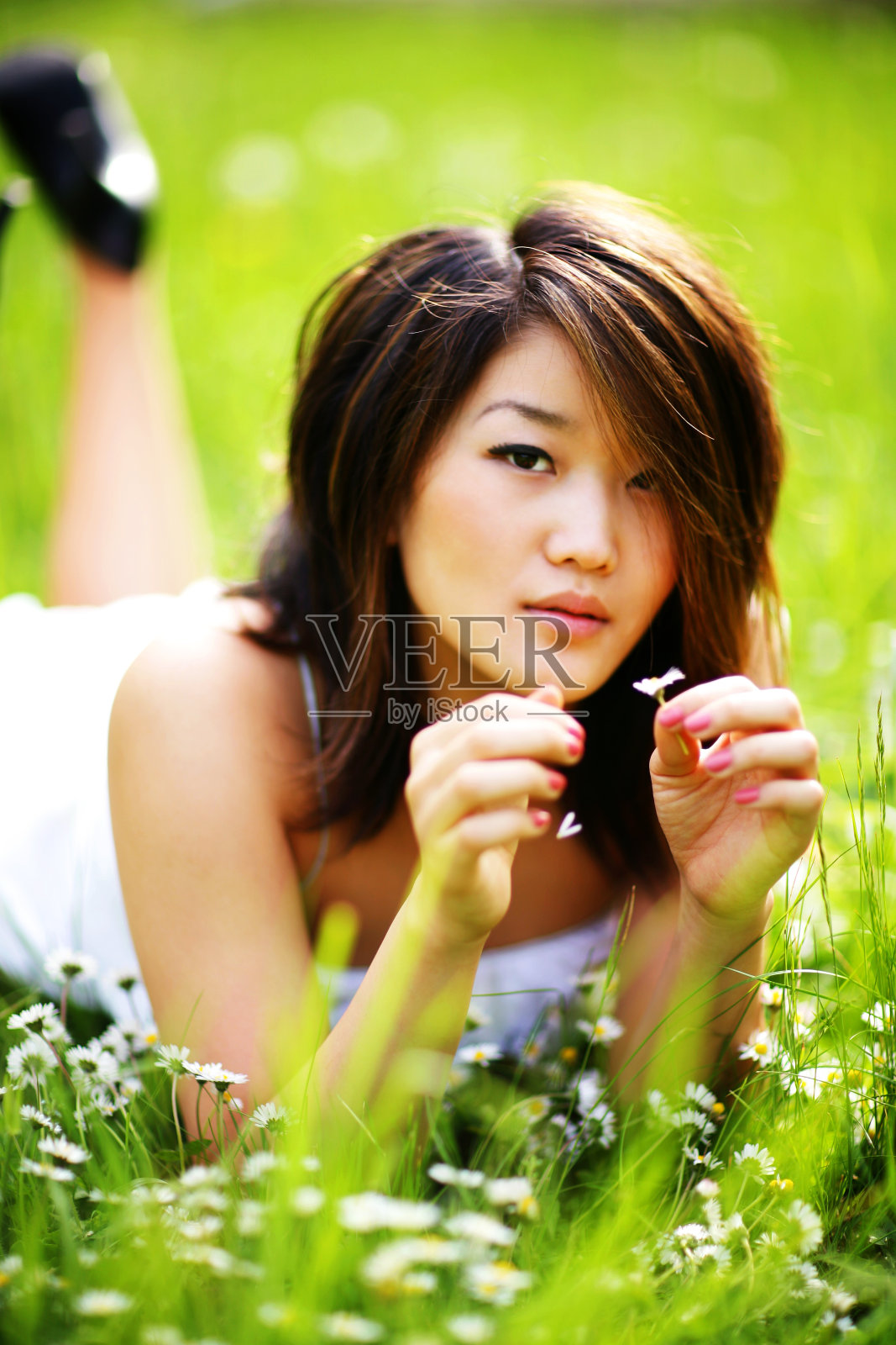 亚洲女孩躺在肚子上摘花照片摄影图片