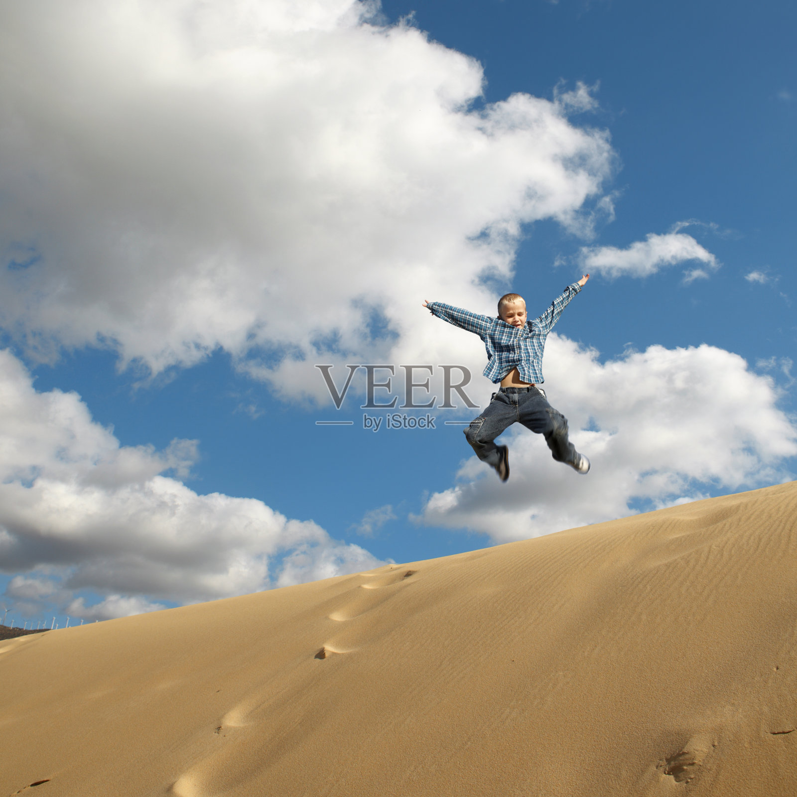 男孩在沙丘上跳照片摄影图片