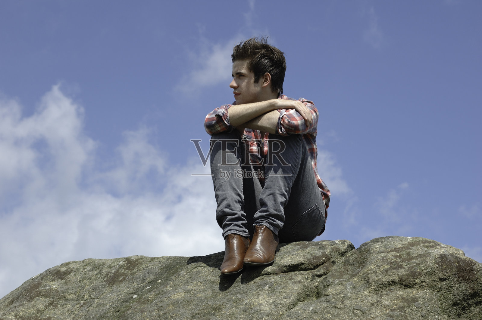 有魅力的年轻人坐在一块石头上照片摄影图片