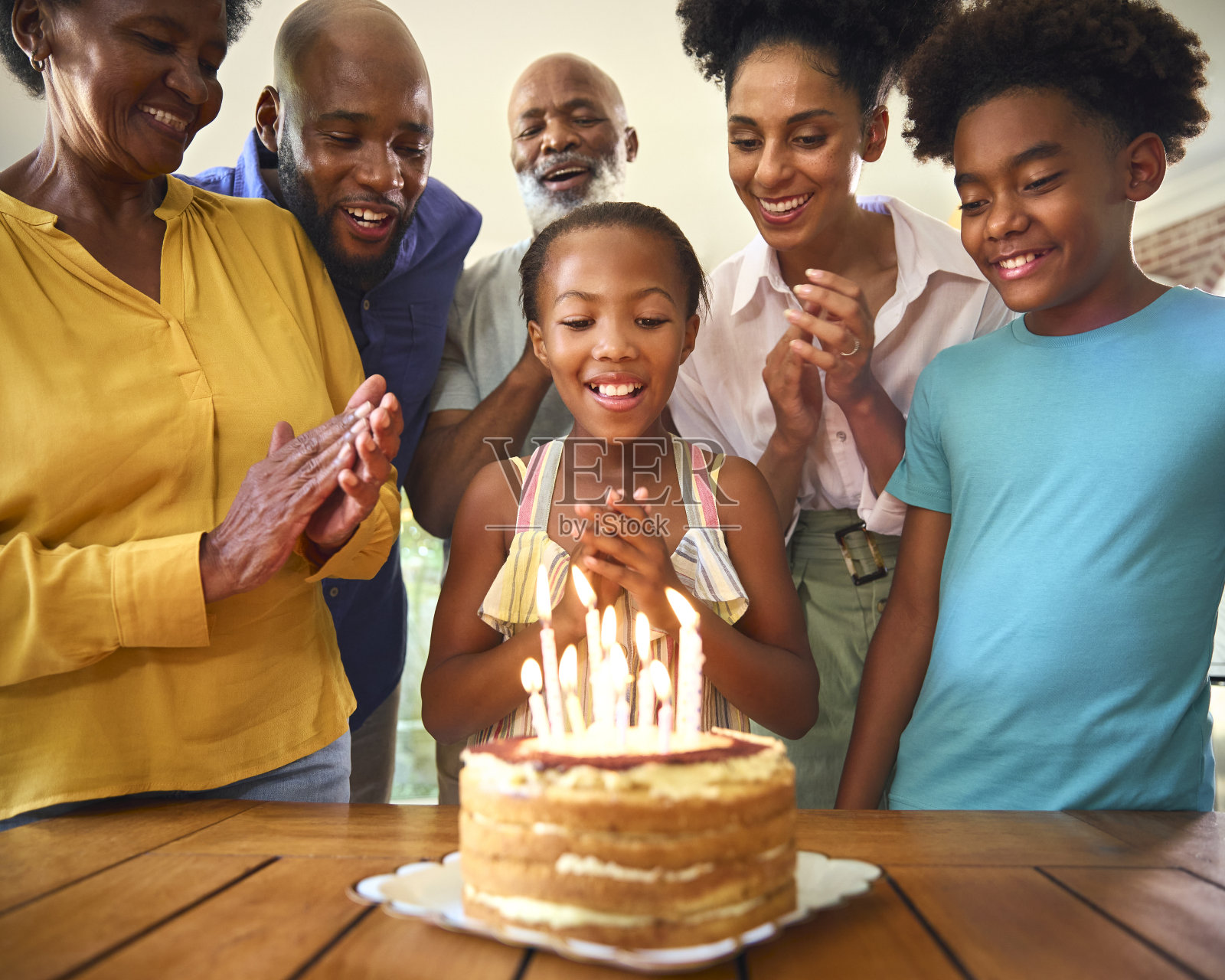 几代同堂的家庭在家里用蛋糕和蜡烛庆祝孙女的生日照片摄影图片