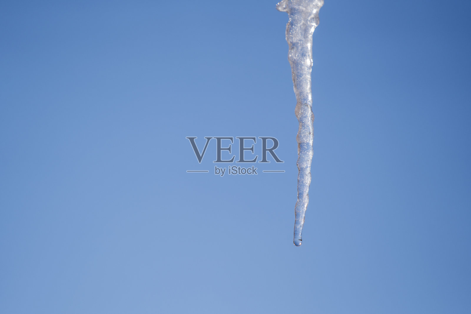 在一个阳光明媚的春日，冰冻的冰柱孤立在蓝天的背景上照片摄影图片