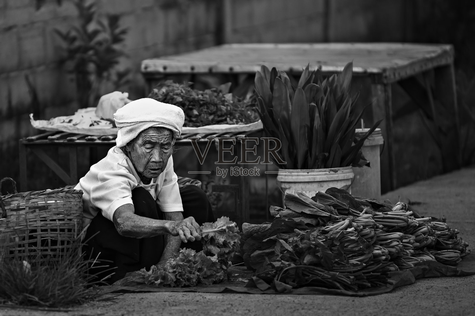 一位老妇人坐在街上卖菜。照片摄影图片