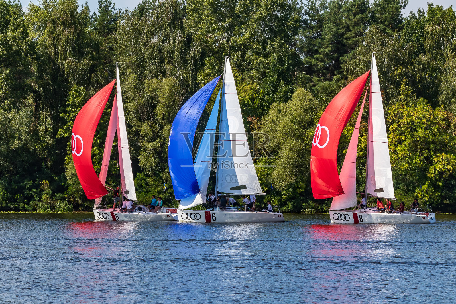 红色，白色，蓝色船帆的白色游艇。照片摄影图片
