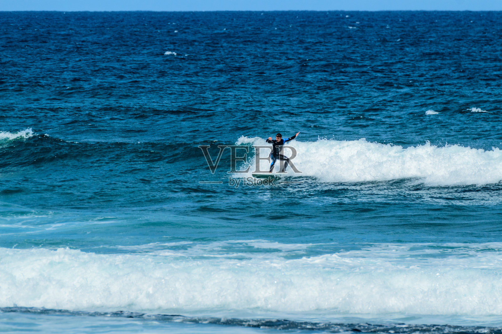 西班牙裔黑发男子在拉斯美洲海滩上乘风而上。照片摄影图片