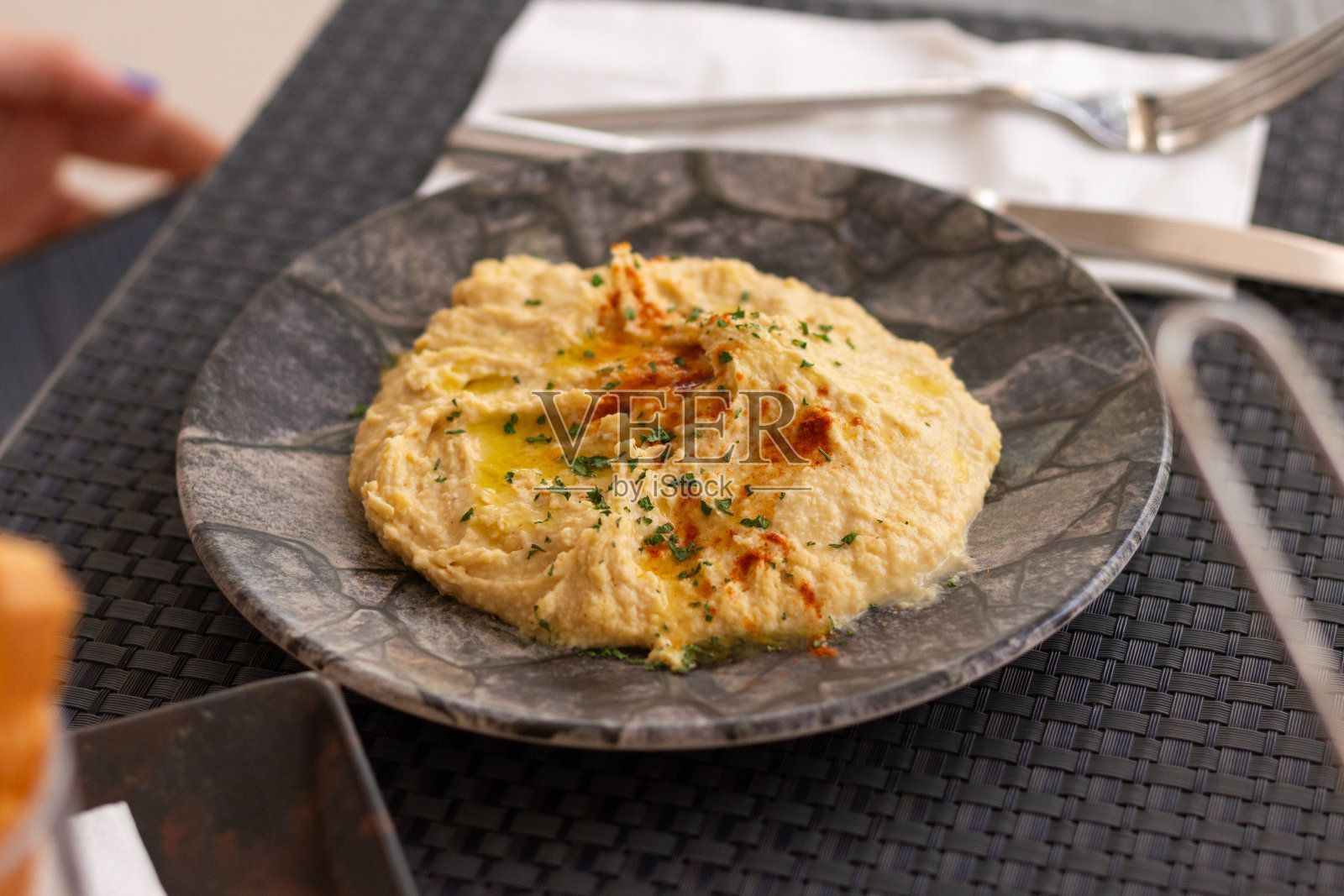 鹰嘴豆泥。餐厅里用红辣椒和香草装饰的一大碗鹰嘴豆泥照片摄影图片