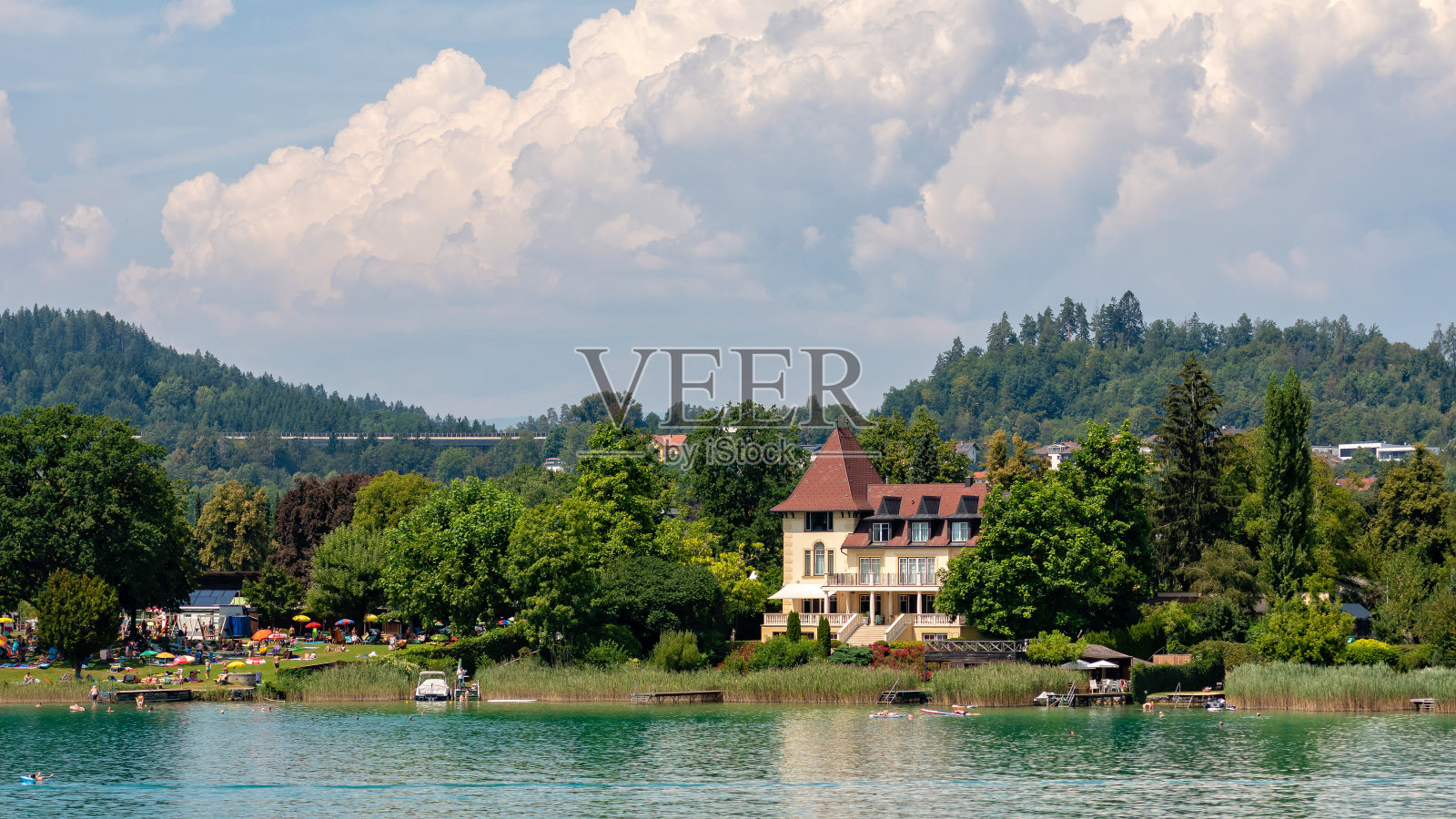 从船上看到的湖岸美景：建筑、山脉、森林和公路照片摄影图片